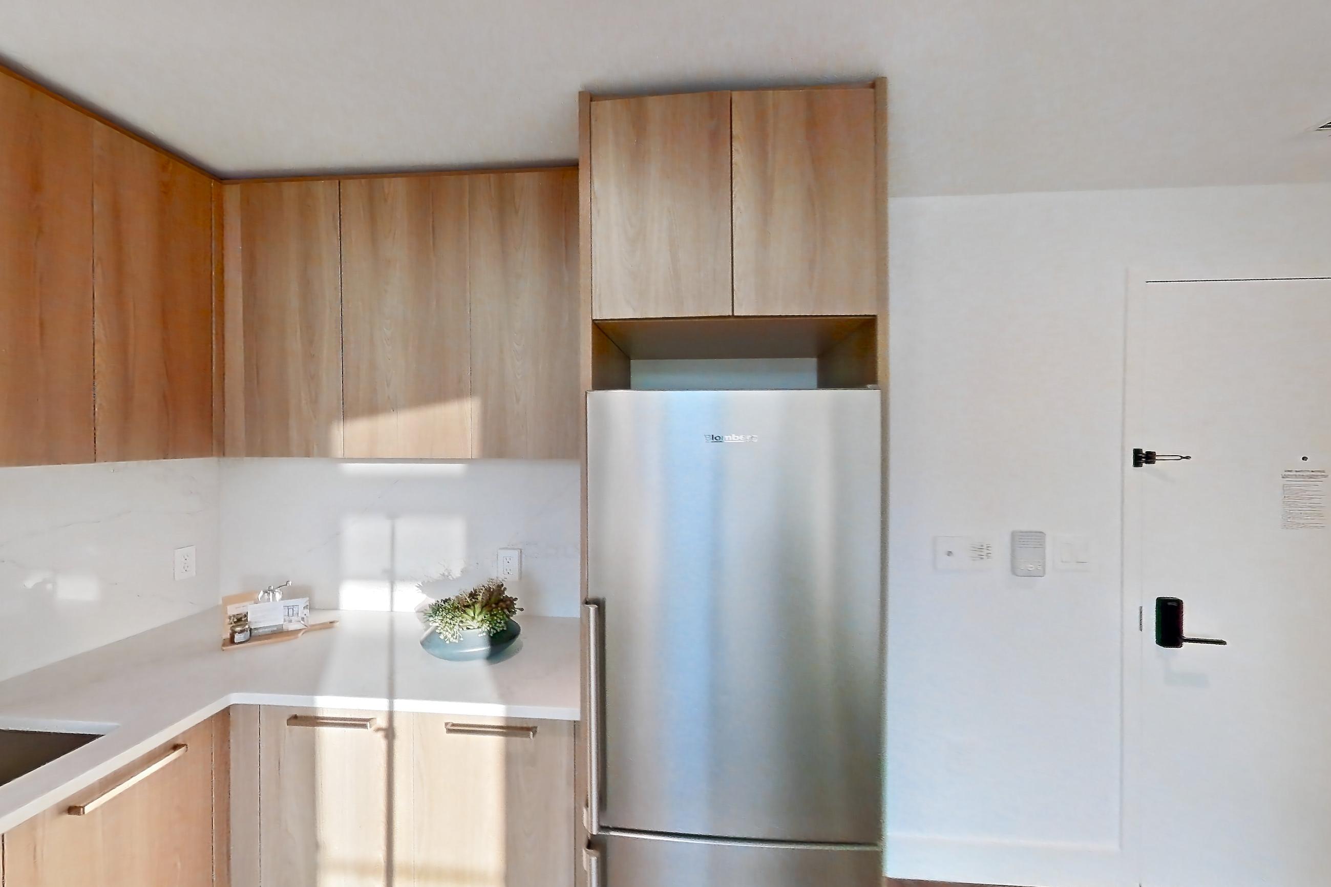 Kitchen with electric range, light countertops, light stone countertops, light wood-finish flooring, oven/range, refrigerator, and stainless steel appliances, Unit 0418 at Hearthstone
