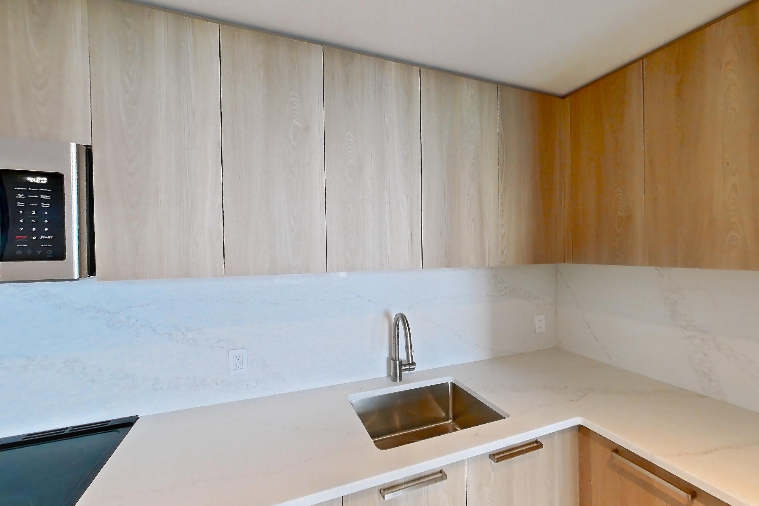 Kitchen with electric range, light countertops, light stone countertops, light wood-finish flooring, oven/range, and stainless steel appliances, Unit 0807 at Hearthstone
