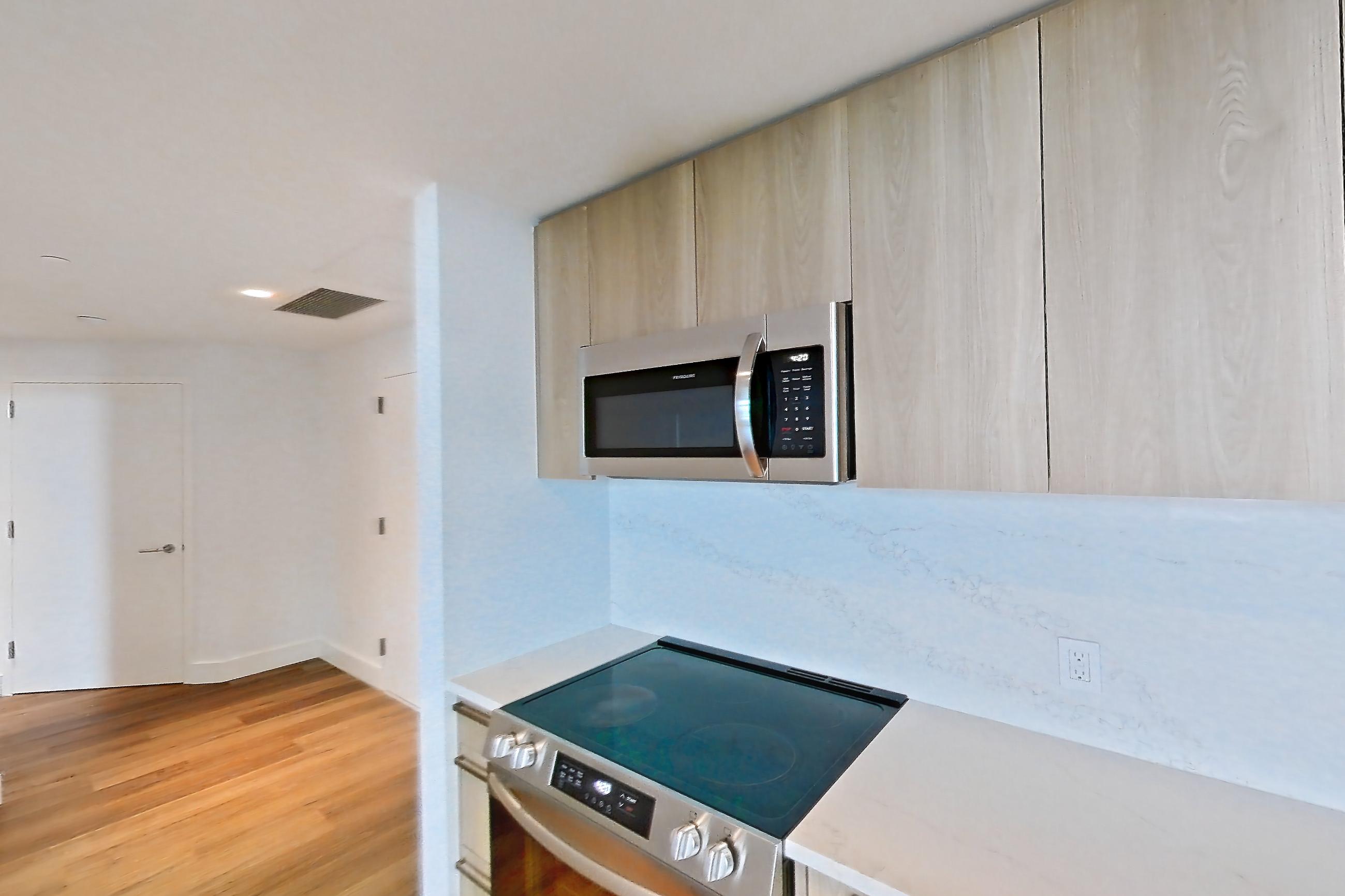 Kitchen with electric range, light countertops, light stone countertops, light wood-finish flooring, oven/range, and stainless steel appliances, Unit 0807 at Hearthstone