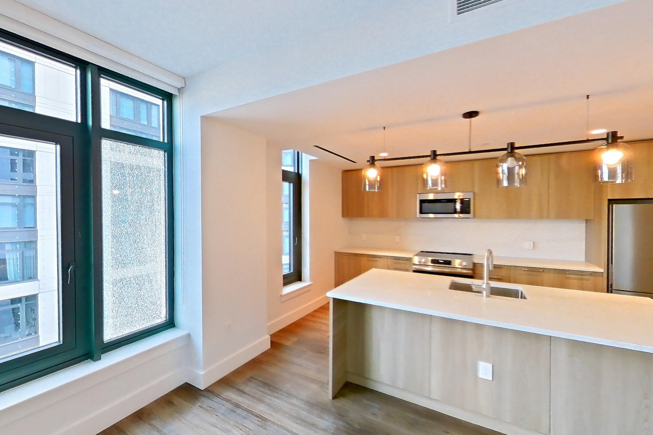 Living room with dark wood-finish flooring, electric range, kitchen island, light stone countertops, light wood-finish flooring, microwave, oven/range, refrigerator, and stainless steel appliances, Unit 0625 at Hearthstone