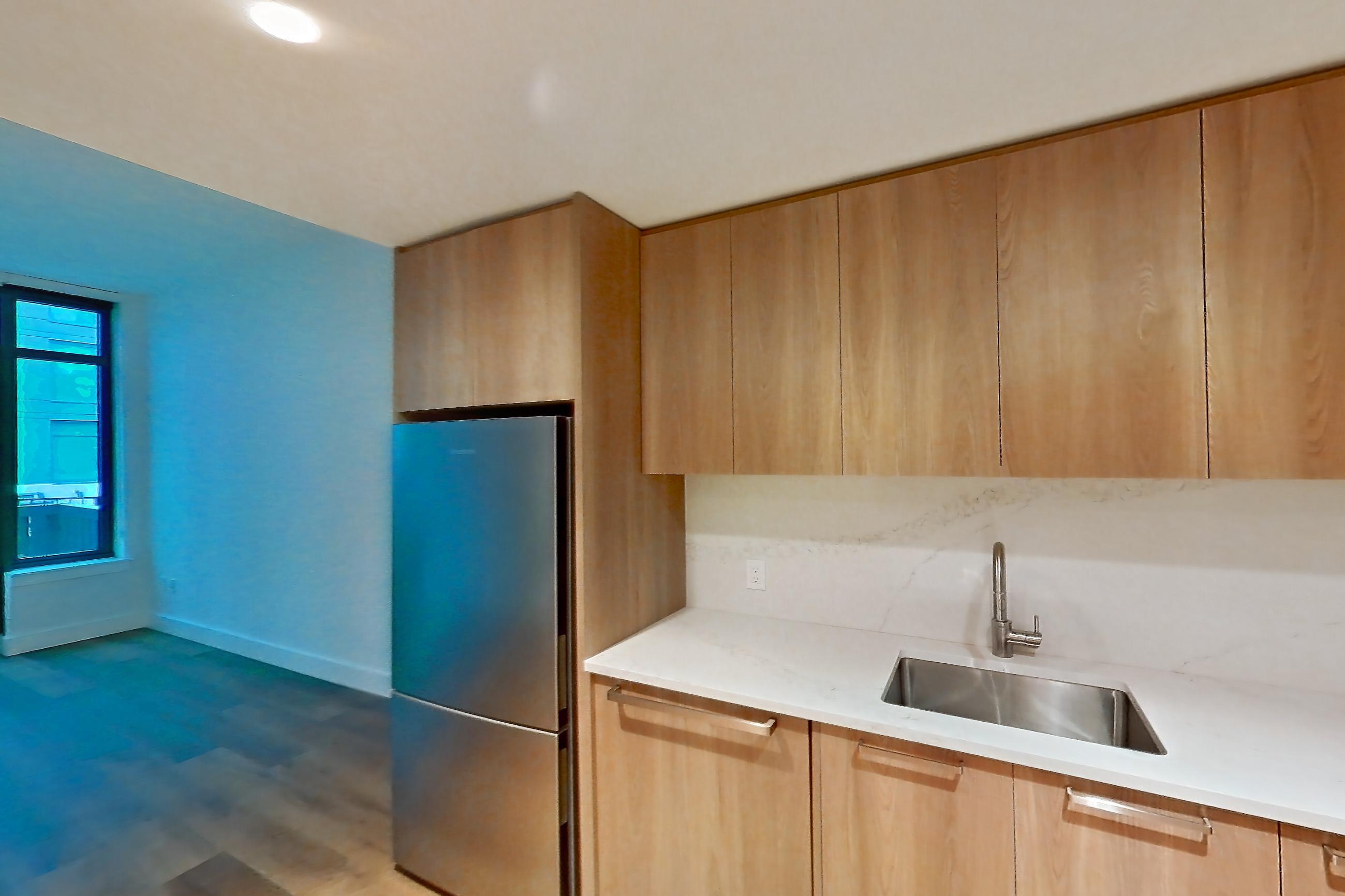 Kitchen with electric range, light countertops, light stone countertops, light wood-finish flooring, microwave, oven/range, refrigerator, and stainless steel appliances, Unit 0231 at Hearthstone