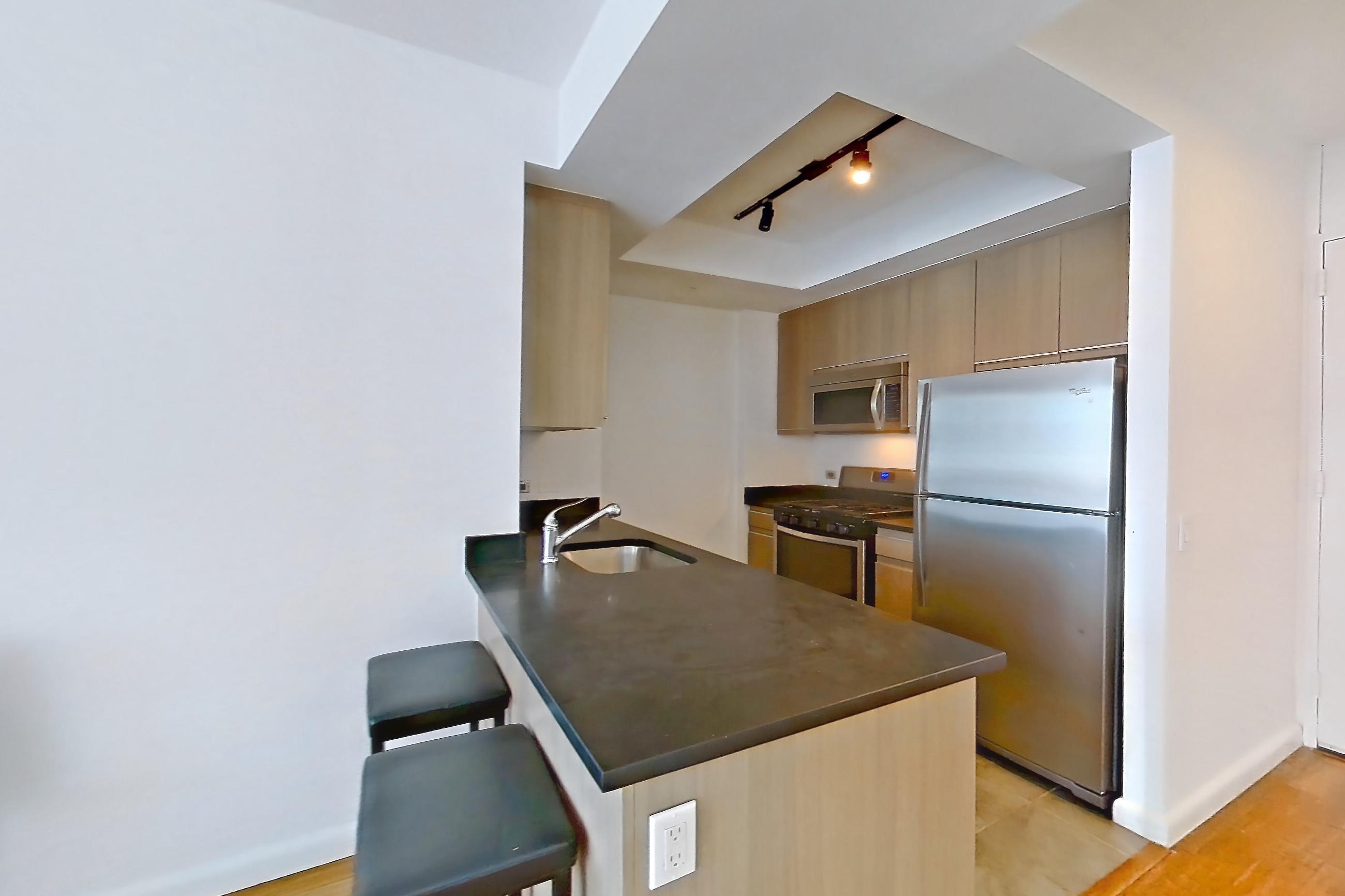 Living space with dark countertops, gas range, light wood-finish flooring, and wood-finish flooring, Apartment 16A at 66 Rockwell