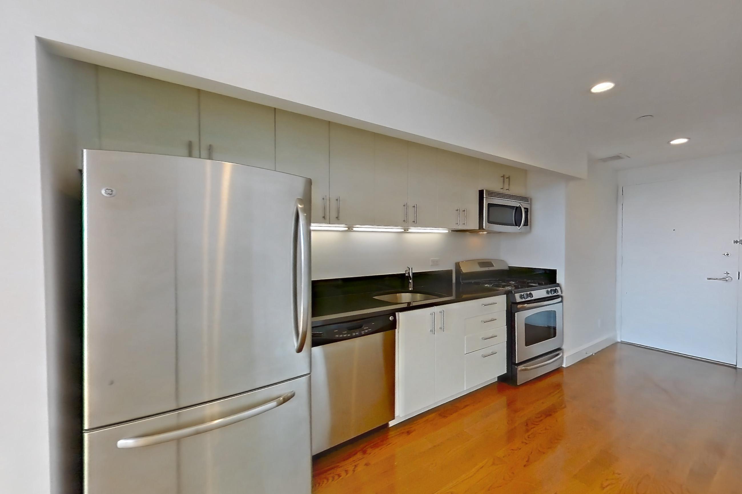 Living space with dark countertops, dishwasher, light countertops, light wood-finish flooring, refrigerator, stainless steel appliances, and white appliances, Apartment 10M at The Addison