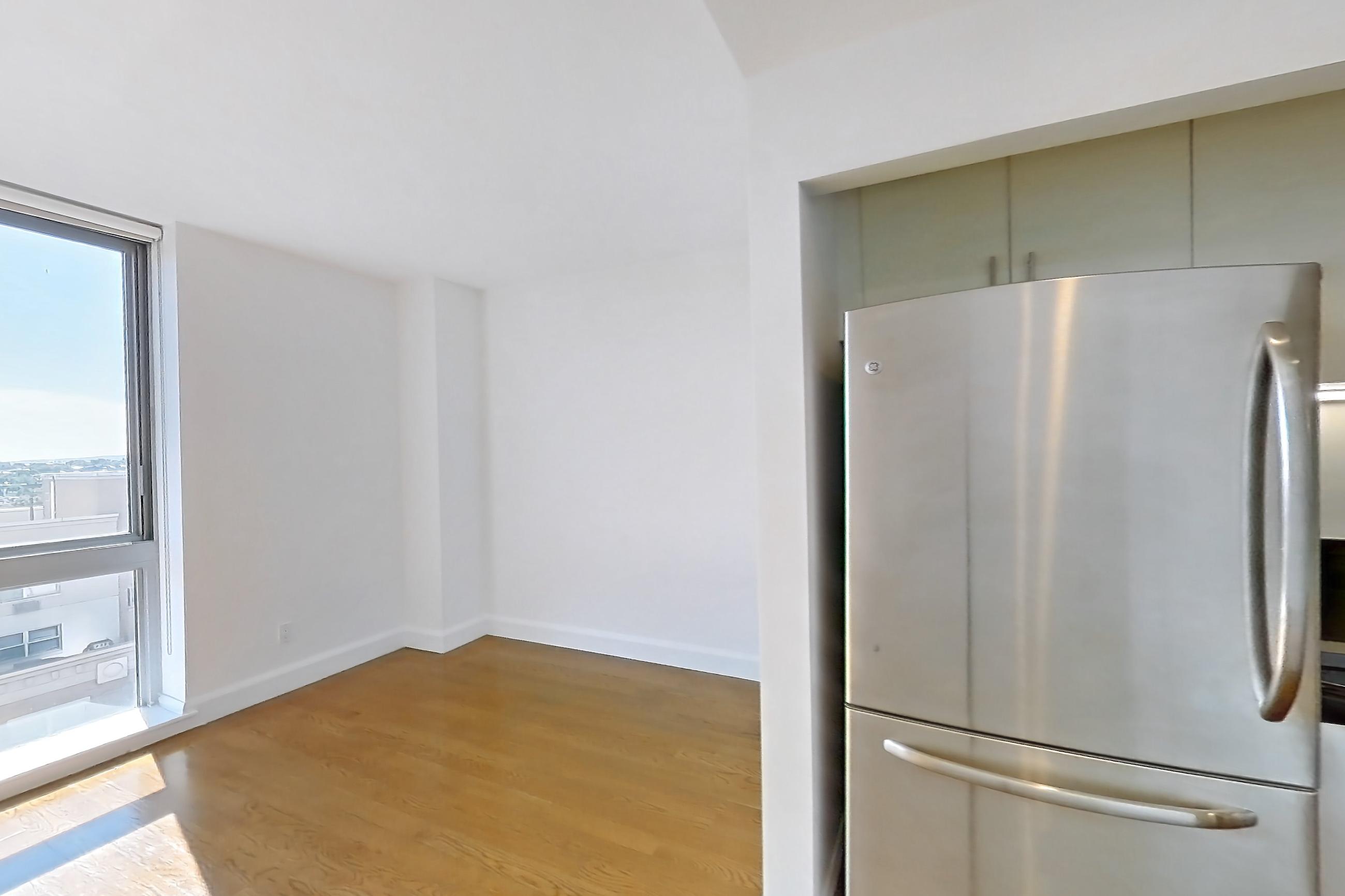 Living space with dark countertops, dishwasher, light countertops, light wood-finish flooring, refrigerator, stainless steel appliances, and white appliances, Apartment 10M at The Addison