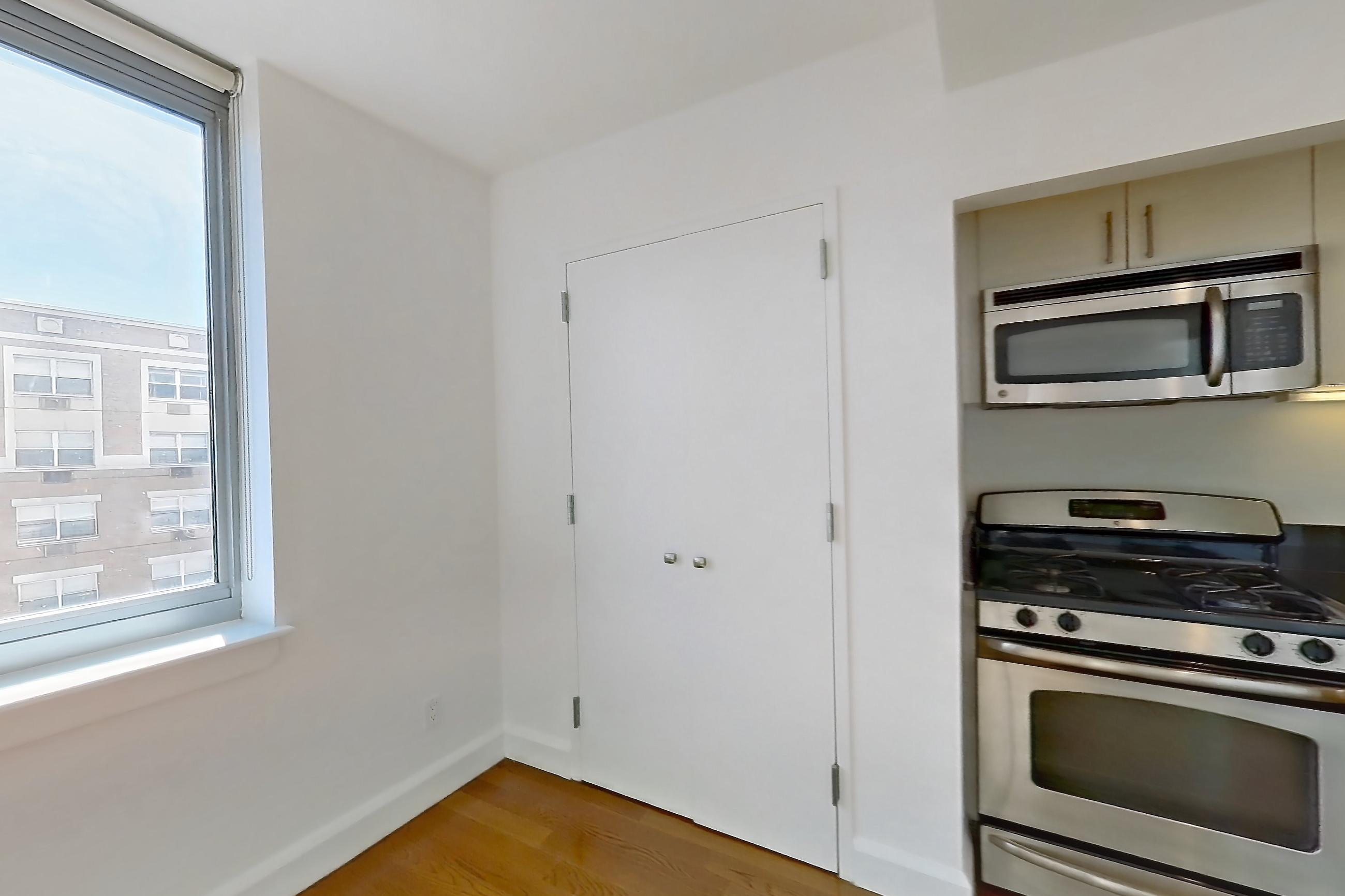 Living space with dark countertops, gas range, light countertops, light wood-finish flooring, microwave, oven/range, and stainless steel appliances, Apartment 7K at The Addison