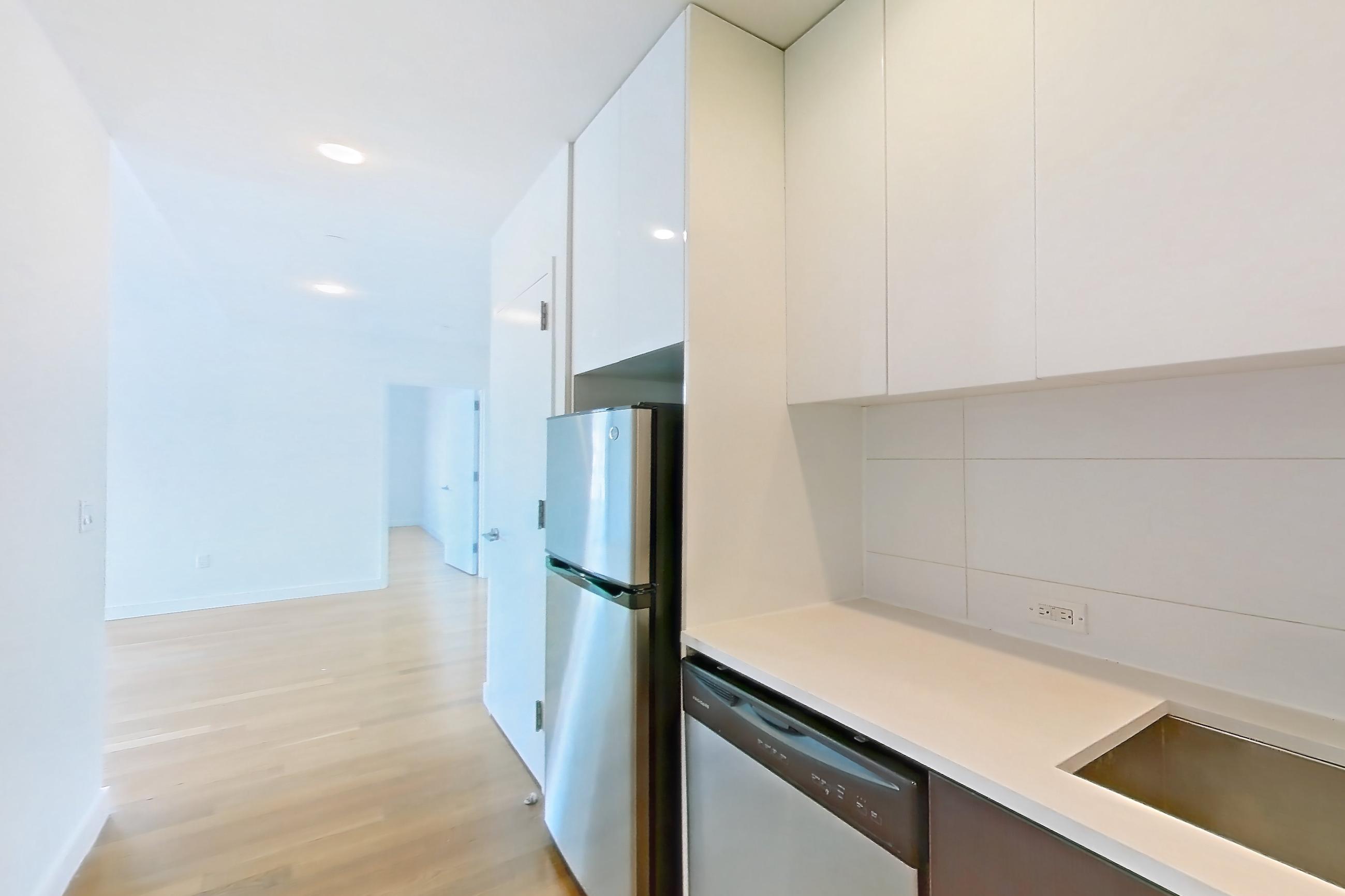 Kitchen with black appliances, dishwasher, gas range, light countertops, light wood-finish flooring, microwave, oven/range, refrigerator, stainless steel appliances, and wood-finish flooring, Apartment 707 at The Bergen
