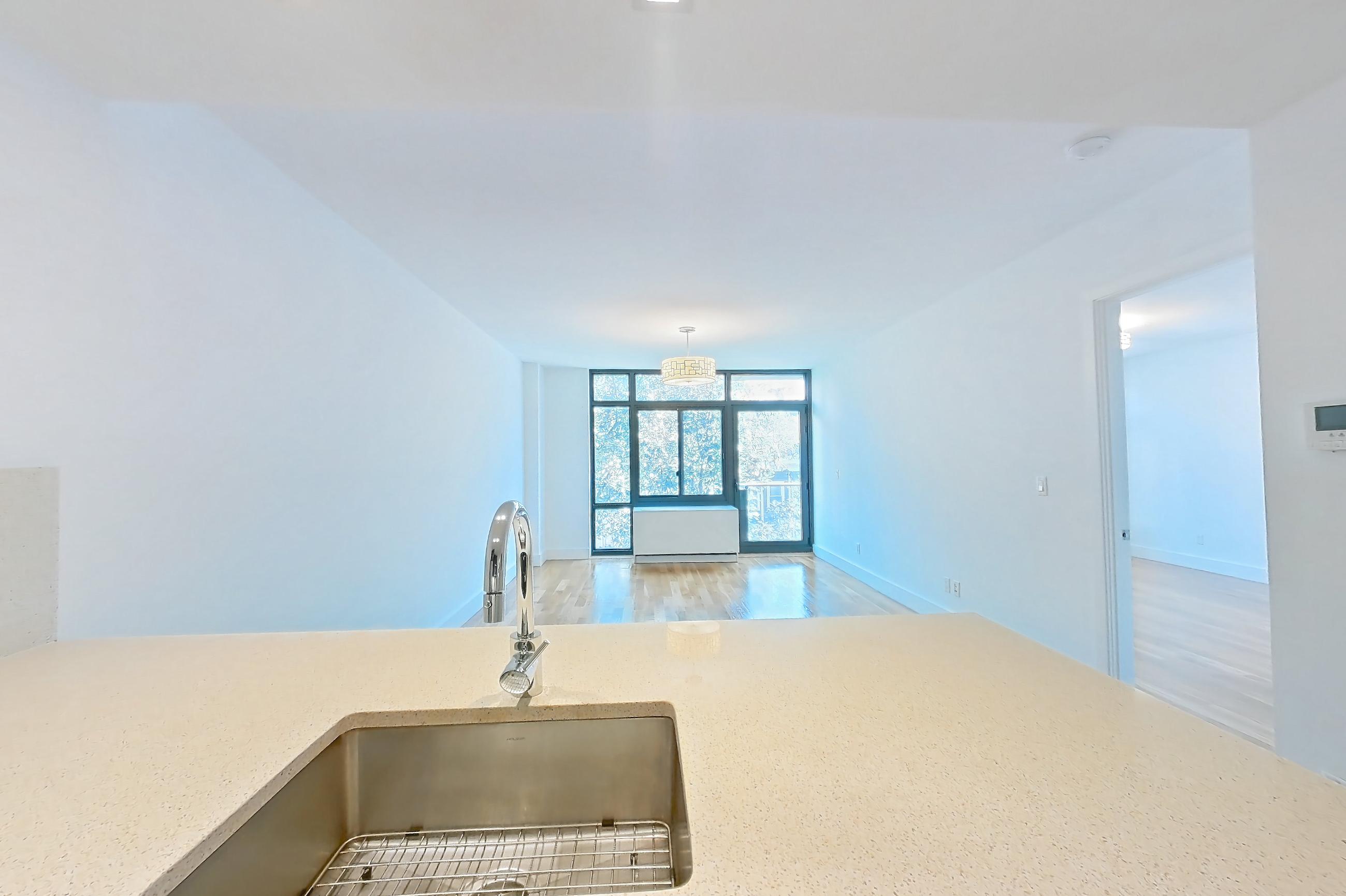 Kitchen with cooktop, dishwasher, gas cooktop, kitchen island, light stone countertops, light wood-finish flooring, oven/range, refrigerator, and stainless steel appliances, Apartment 3L at The Kestrel