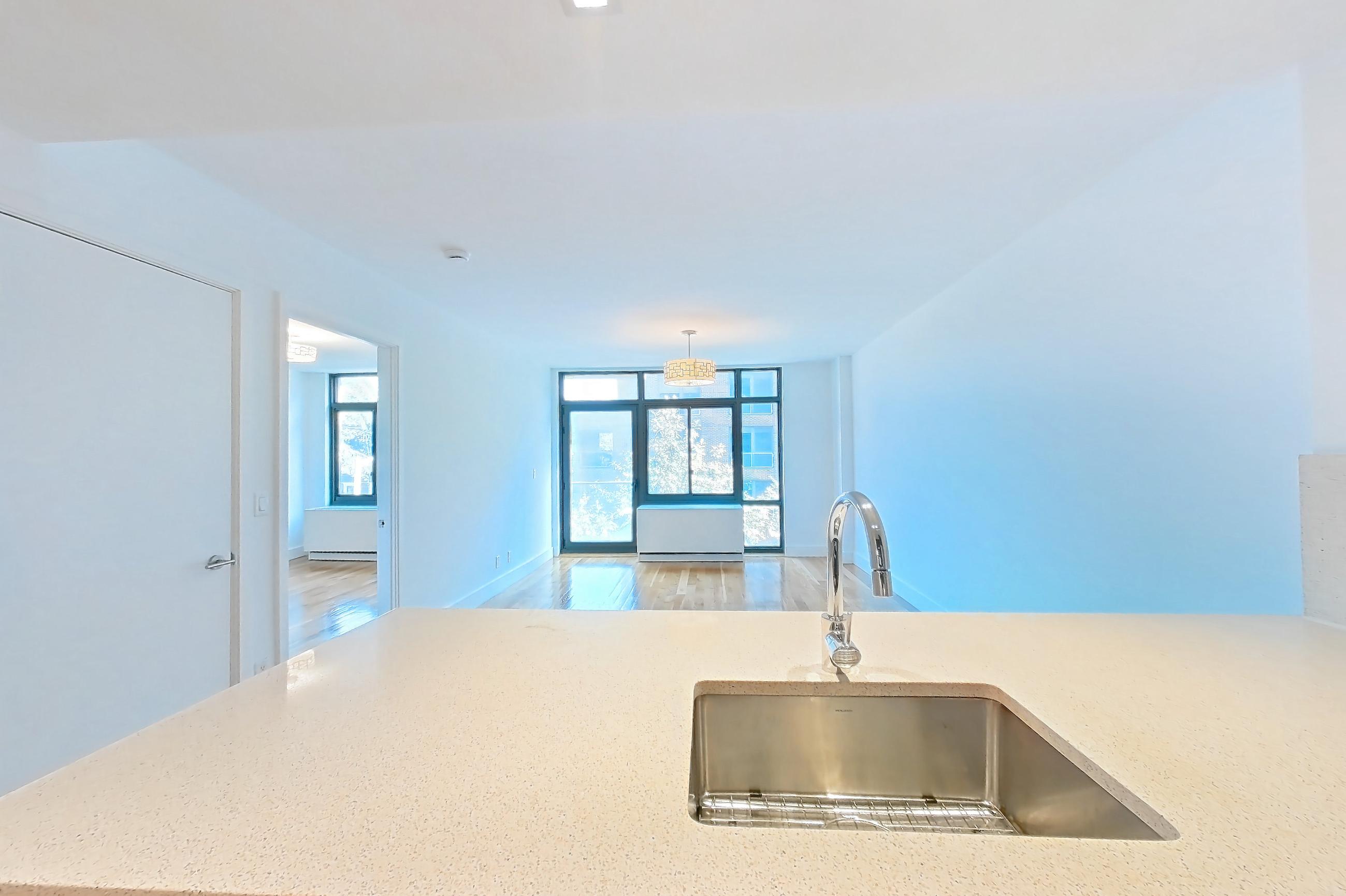 Kitchen with baseboard heating, cooktop, dishwasher, gas cooktop, light stone countertops, light wood-finish flooring, oven/range, refrigerator, and stainless steel appliances, Apartment 3D at The Kestrel