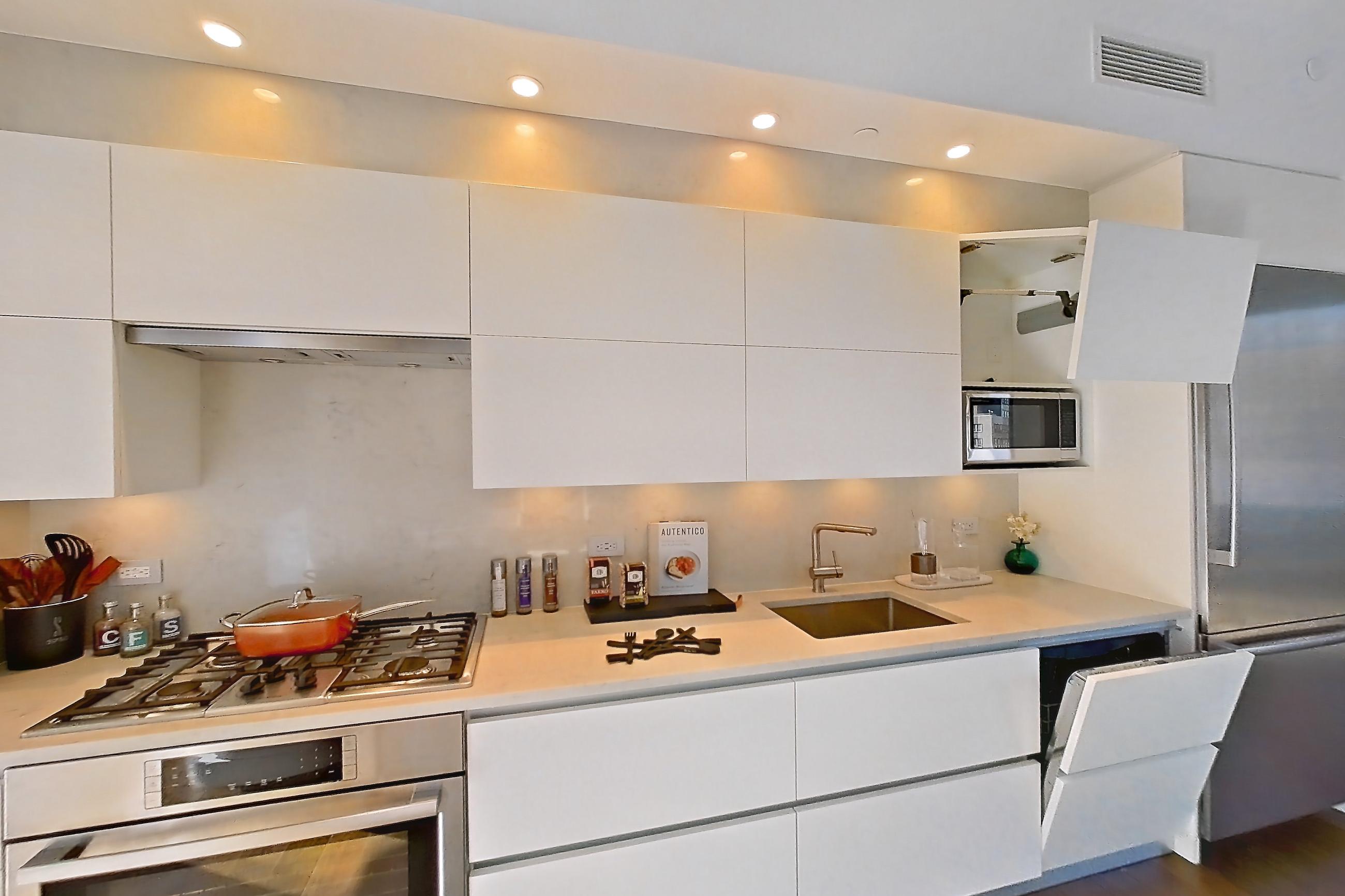 Kitchen with cooktop, dark wood-finish flooring, gas cooktop, light countertops, light wood-finish flooring, oven/range, and stainless steel appliances, Apartment 10E  at Summit NYC