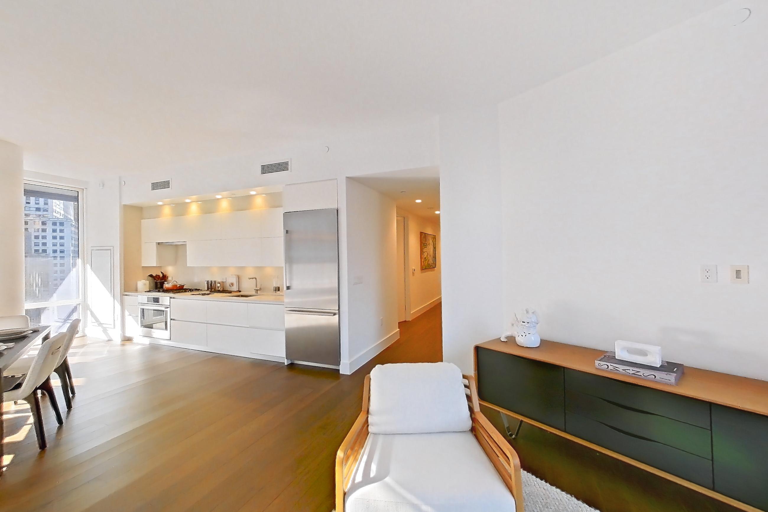 Living room with dark wood-finish flooring, oven/range, refrigerator, and stainless steel appliances, Apartment 10E  at Summit NYC