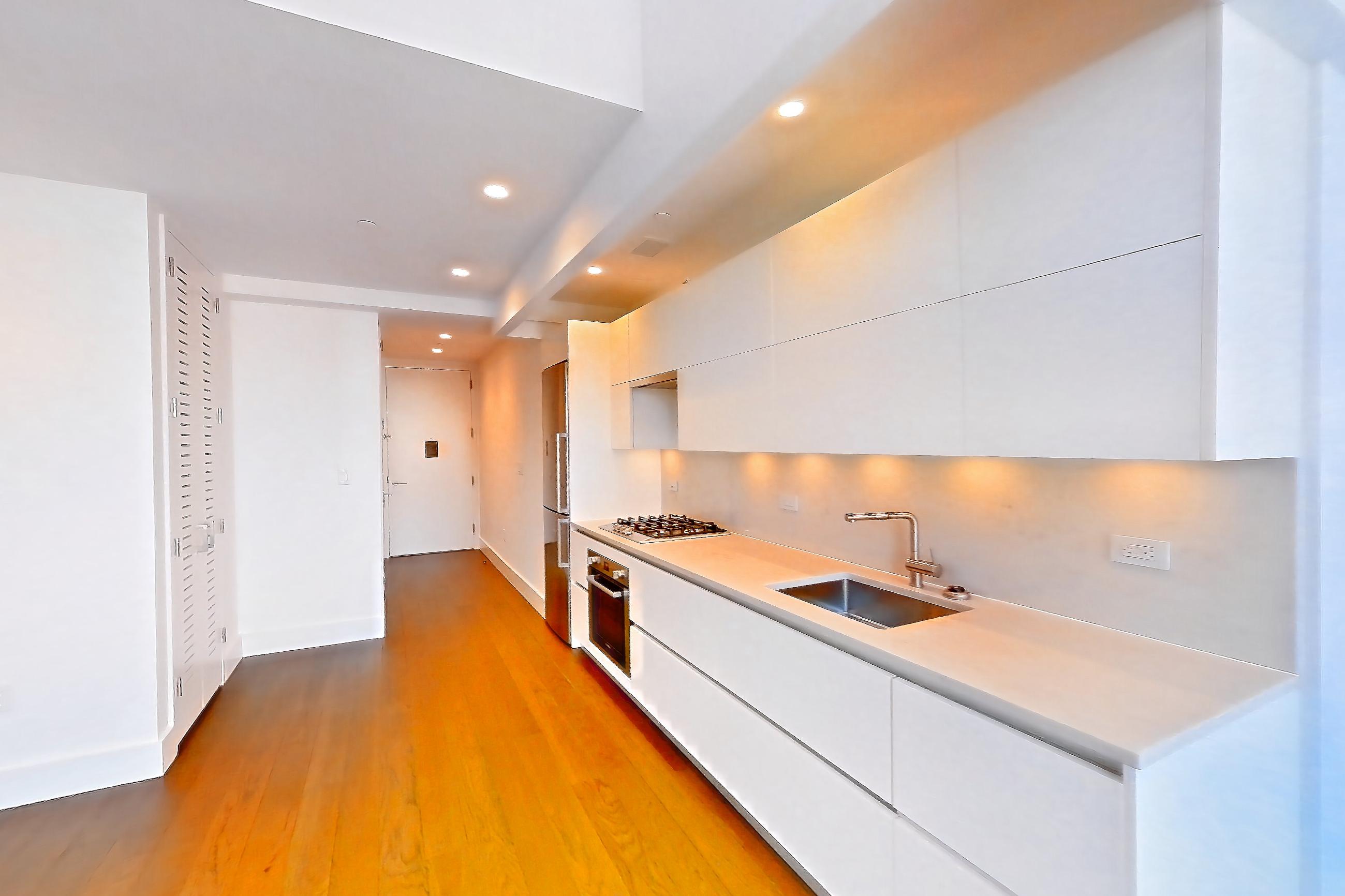 Living space with cooktop, dark wood-finish flooring, gas cooktop, light countertops, stainless steel appliances, and wood-finish flooring, Apartment 26H at Summit NYC