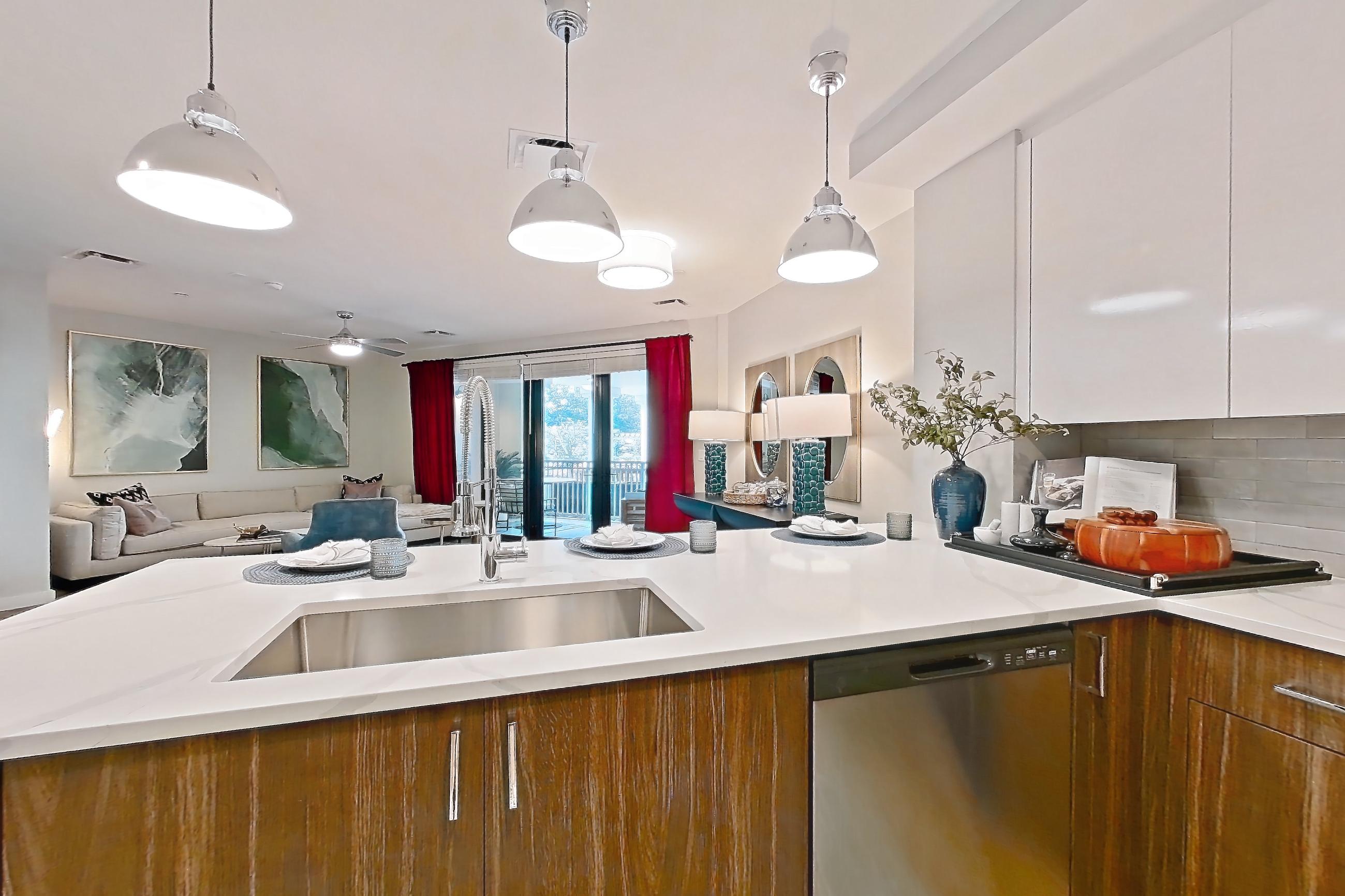 Kitchen with dishwasher, gas range, light countertops, light stone countertops, light wood-finish flooring, microwave, oven/range, and stainless steel appliances, Apartment S213 at Carlow Wind Watch