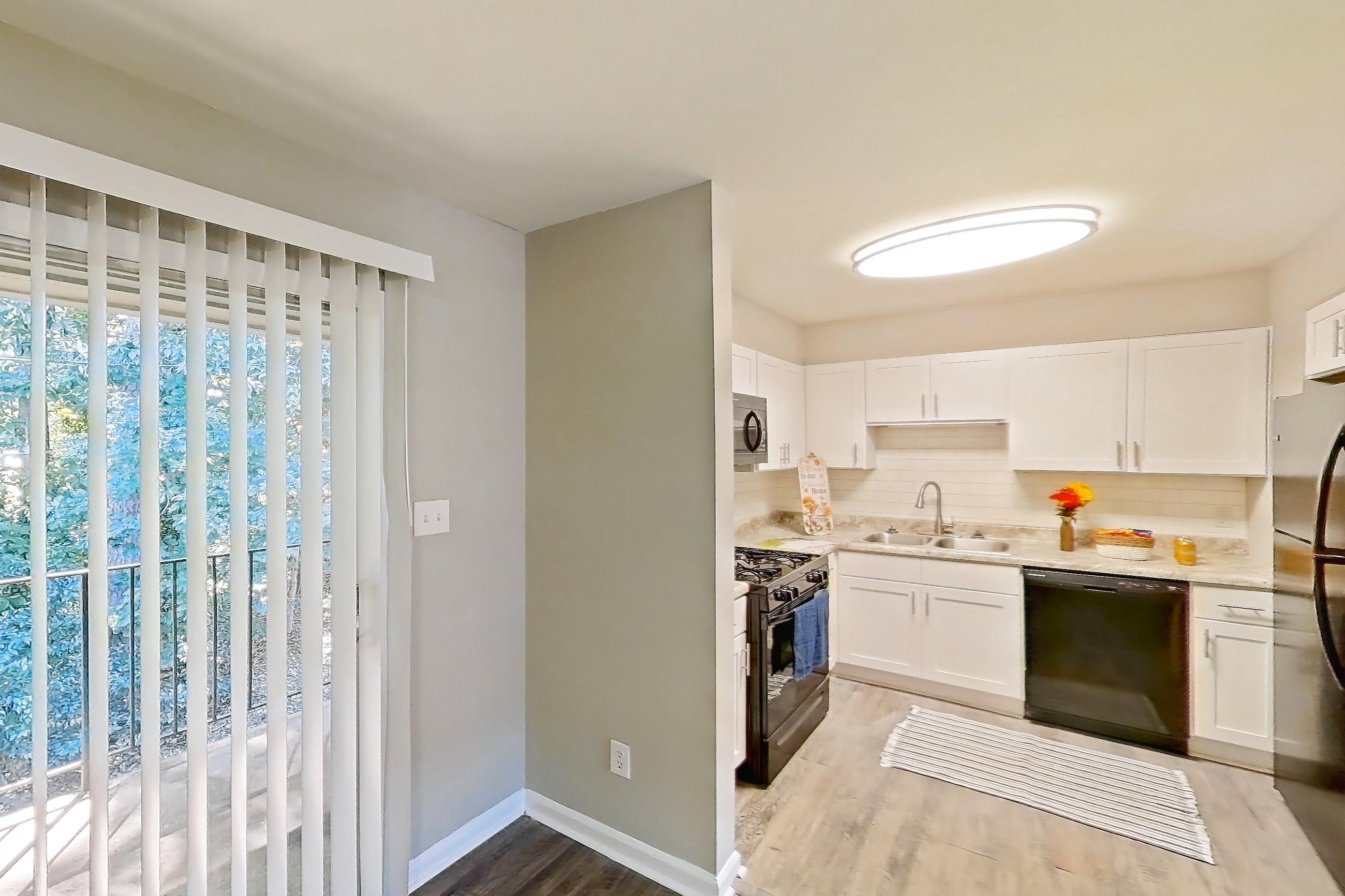 Dining room with black appliances, dishwasher, gas range, light countertops, light wood-finish flooring, refrigerator, and stainless steel appliances, Unit  1280N at Carriage House & Azalea