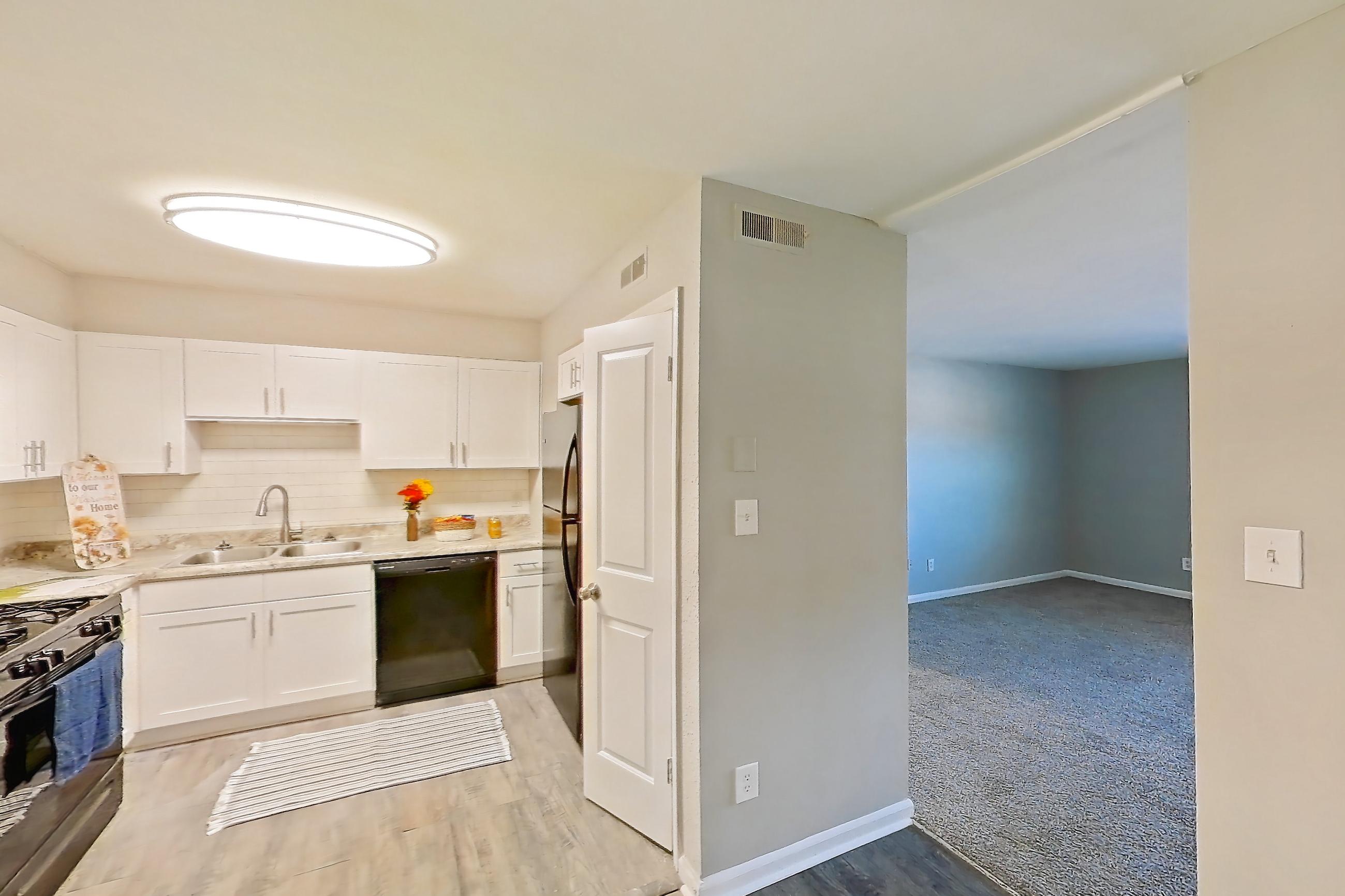 Dining room with black appliances, dishwasher, gas range, light countertops, light wood-finish flooring, refrigerator, and stainless steel appliances, Unit  1280N at Carriage House & Azalea