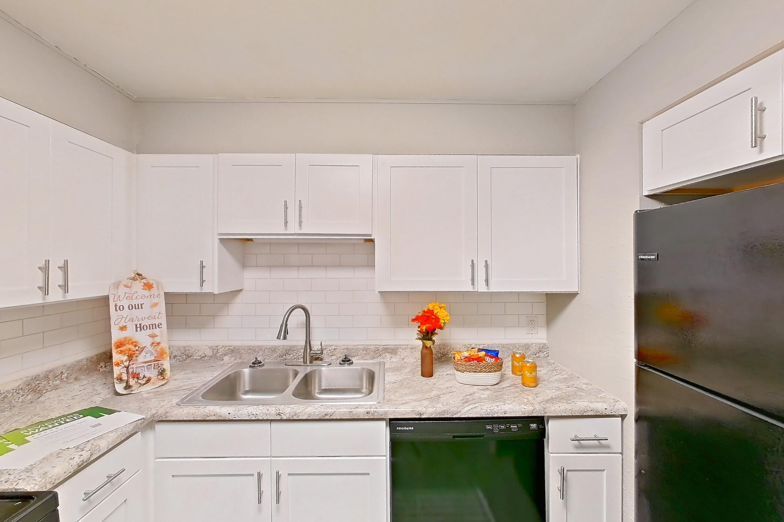 Kitchen with black appliances, dishwasher, gas range, light countertops, light wood-finish flooring, oven/range, range hood, and refrigerator, Unit  1280N at Carriage House & Azalea