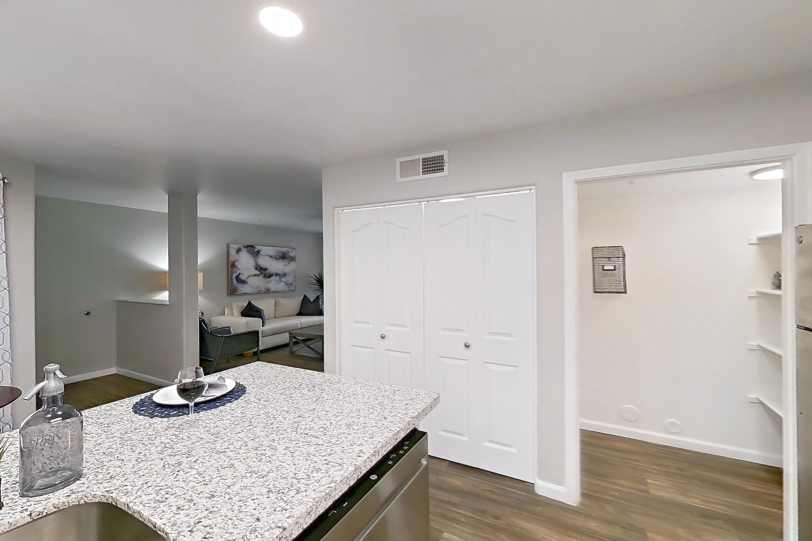 Kitchen with dark wood-finish flooring, dishwasher, electric range, light countertops, light stone countertops, oven/range, refrigerator, and stainless steel appliances, Apartment 1013 at The Palms On Scottsdale