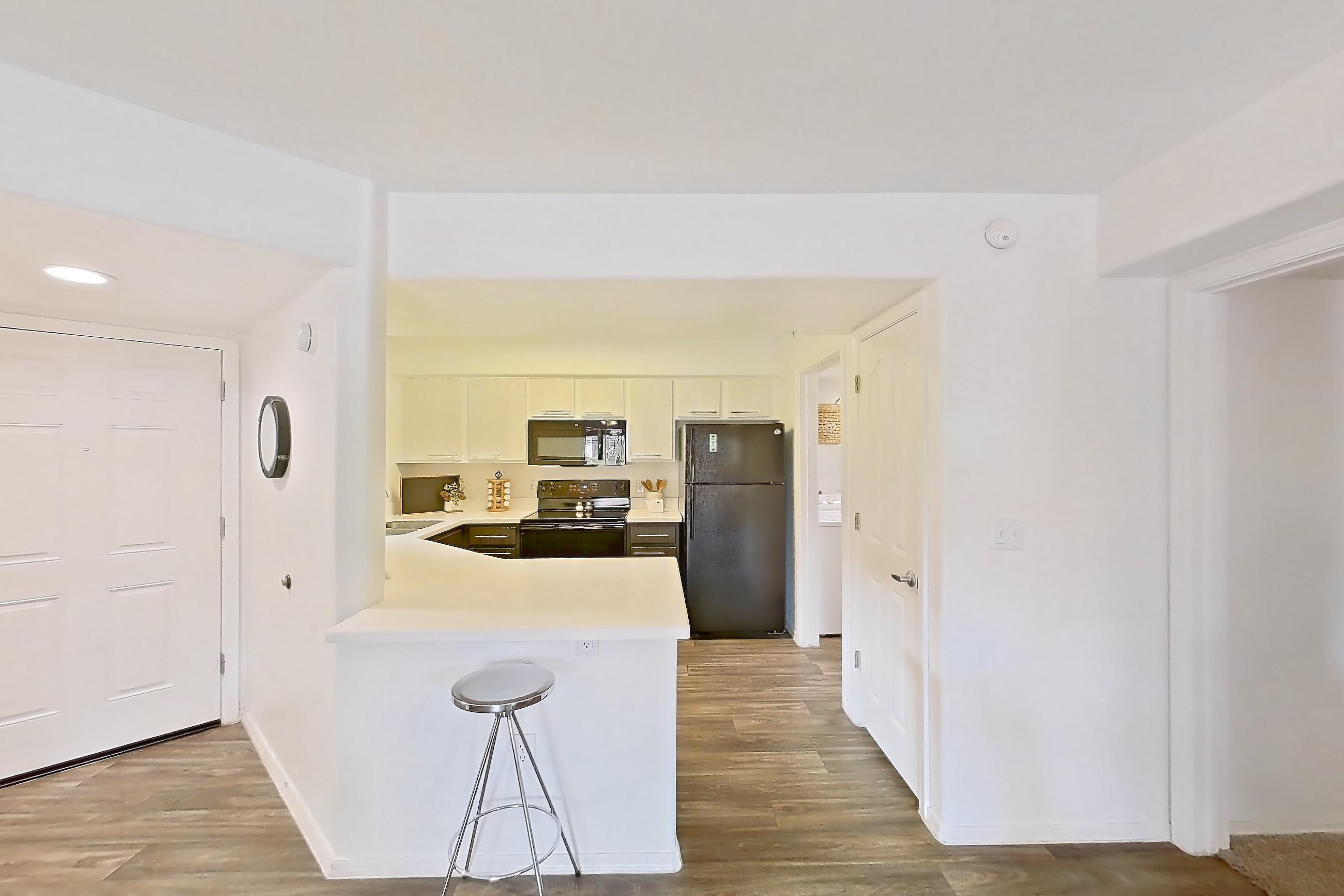 Dining room with black appliances, dark wood-finish flooring, electric range, light countertops, light wood-finish flooring, oven/range, and refrigerator, Apartment 1012 at The Palms On Scottsdale