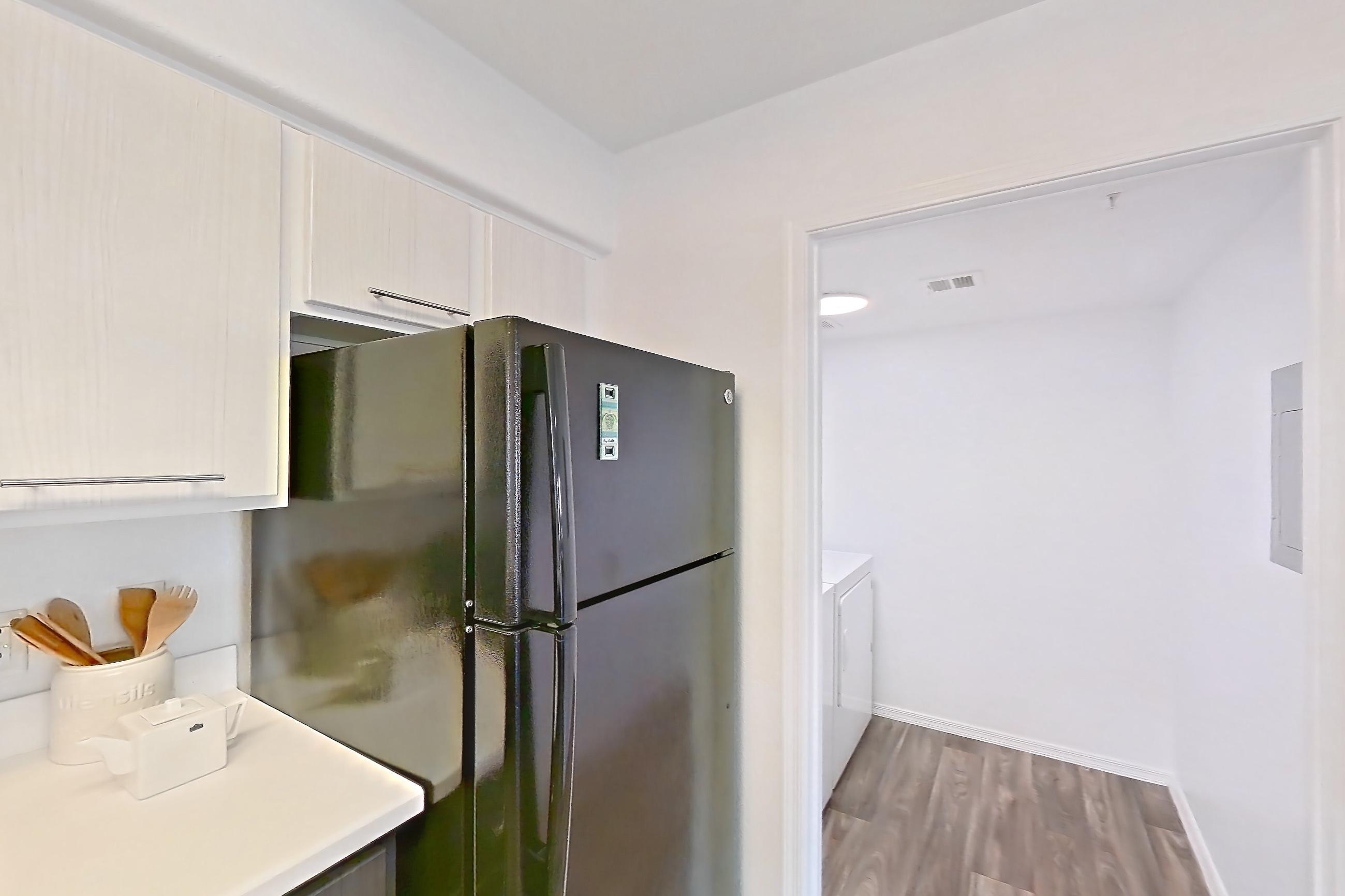 Kitchen with black appliances, dark wood-finish flooring, dishwasher, light countertops, and oven/range, Apartment 1012 at The Palms On Scottsdale