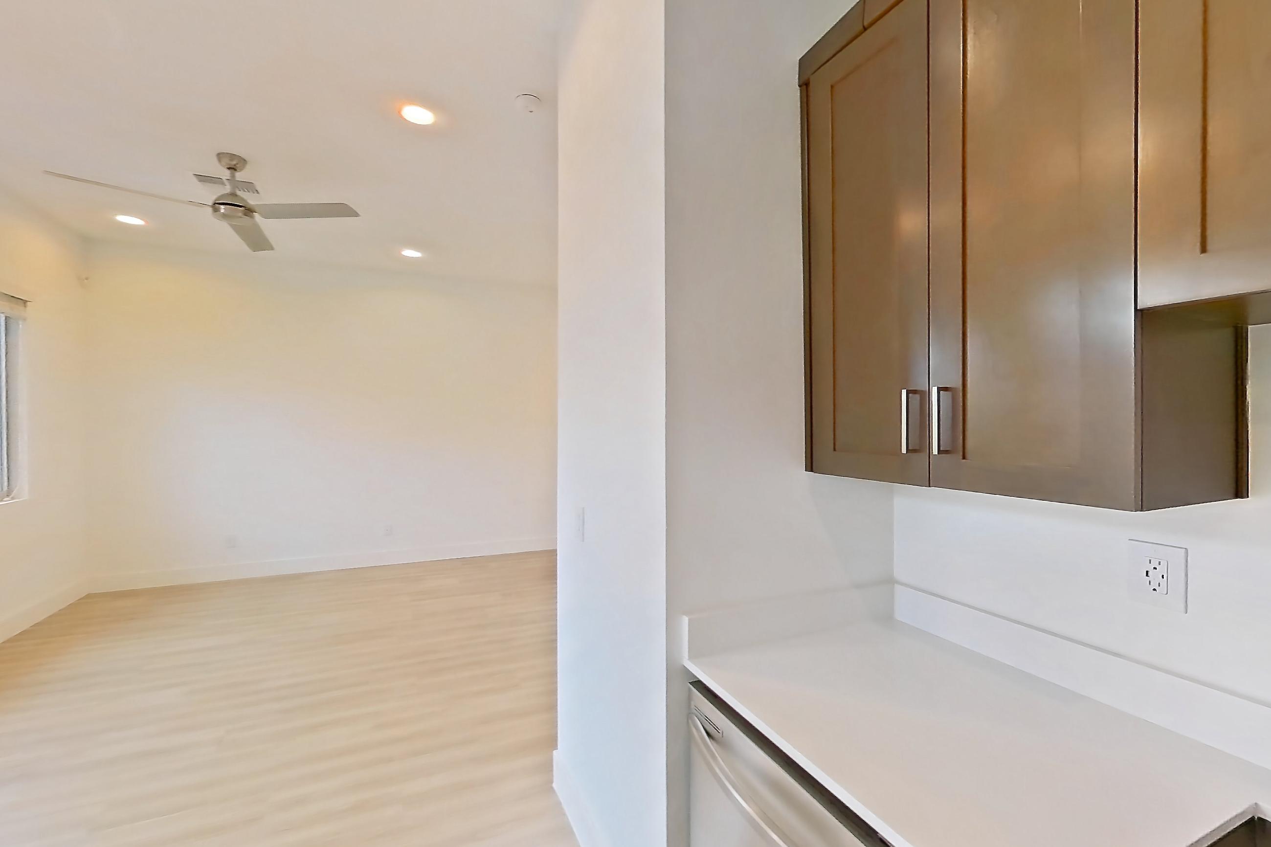 Kitchen with dishwasher, electric range, light countertops, light wood-finish flooring, microwave, oven/range, refrigerator, stainless steel appliances, and water & ice dispenser, Apartment 1A at Tavalo At Cadence
