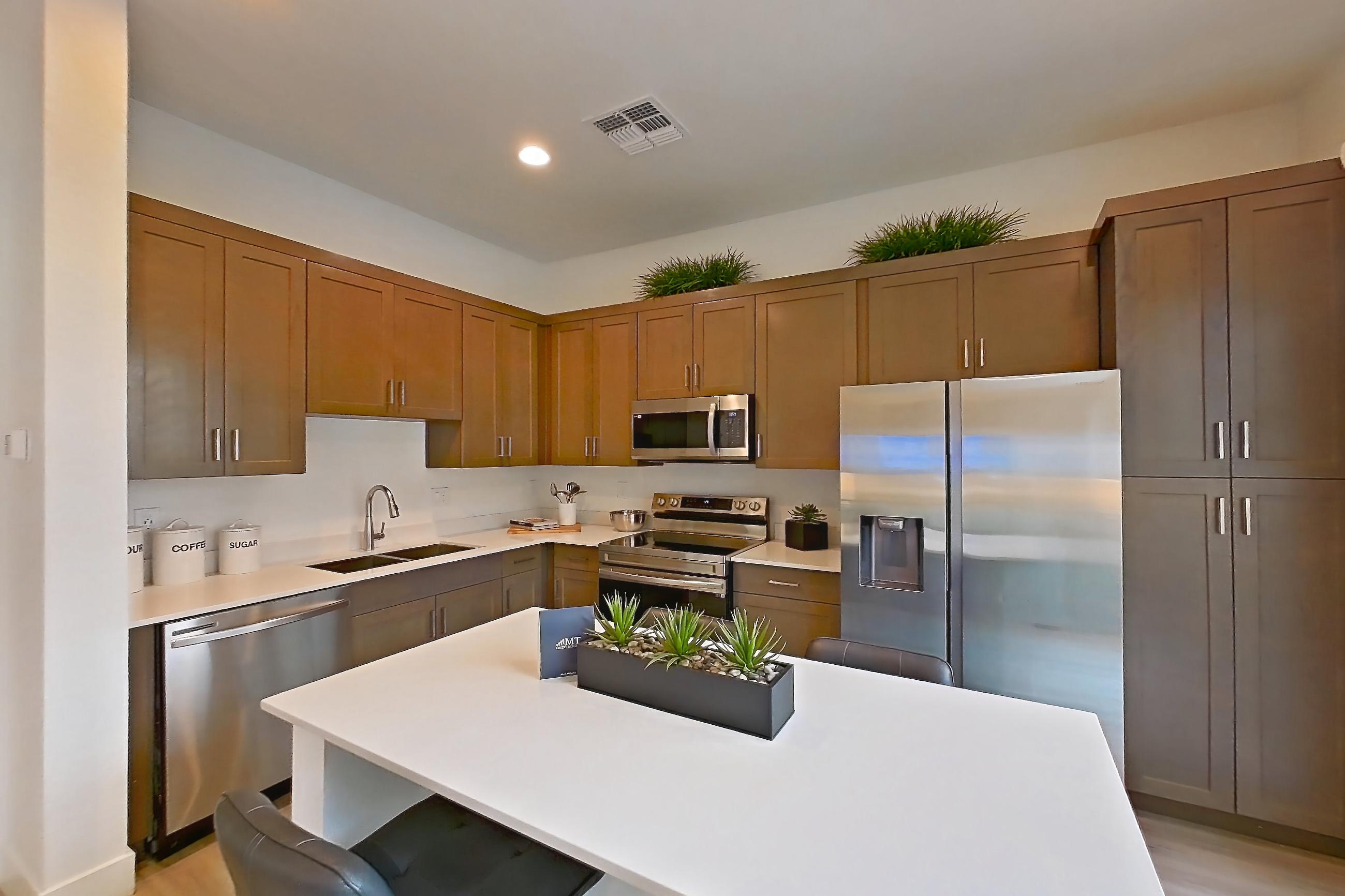 Dining room with dishwasher, electric range, light countertops, light stone countertops, light wood-finish flooring, microwave, oven/range, refrigerator, stainless steel appliances, water & ice dispenser, and white appliances, Apartment 2A at Tavalo At Cadence