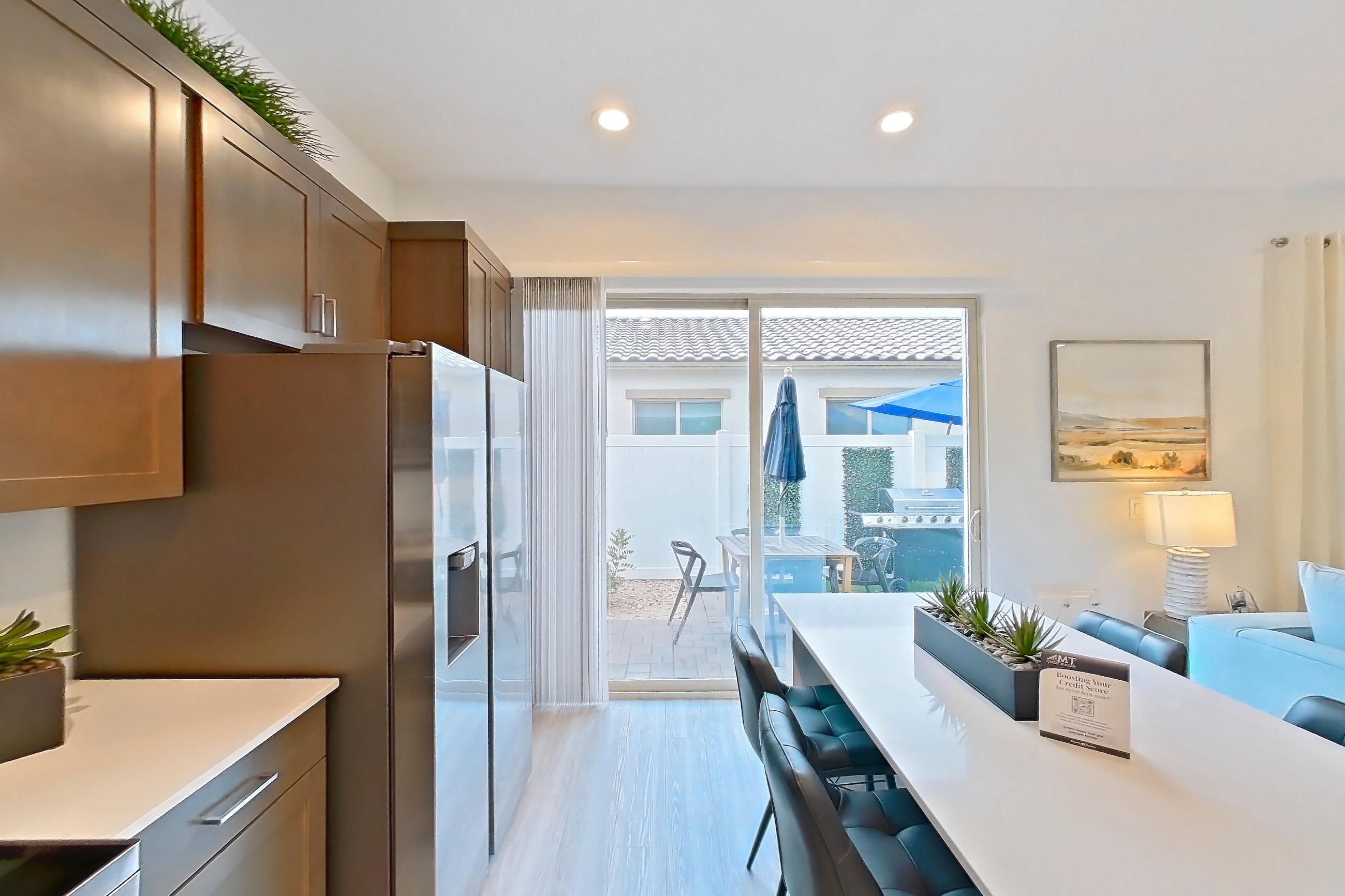 Kitchen with dishwasher, electric range, light countertops, light wood-finish flooring, microwave, oven/range, refrigerator, stainless steel appliances, water & ice dispenser, and white appliances, Apartment 2A at Tavalo At Cadence