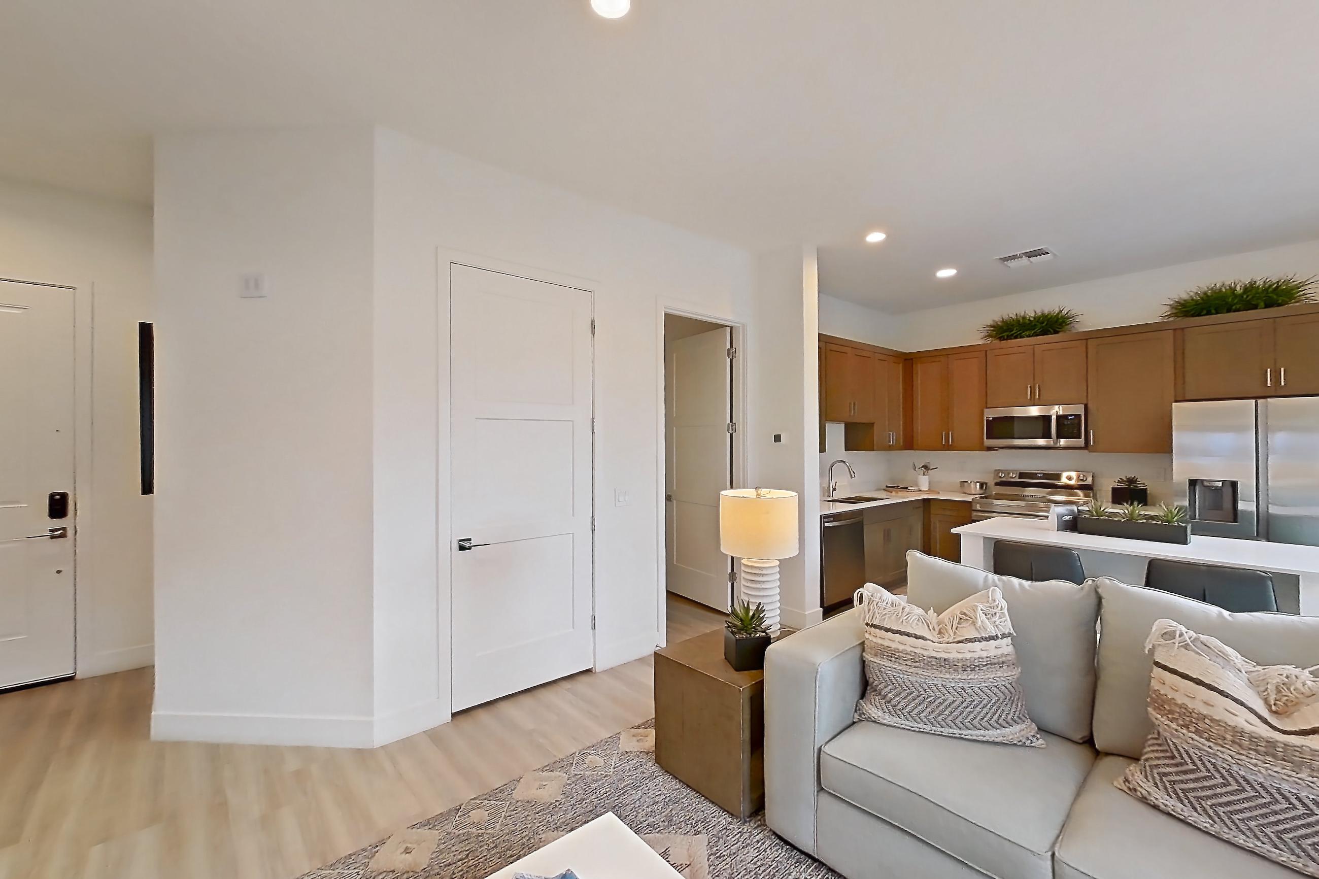 Living room with dishwasher, electric range, light wood-finish flooring, oven/range, and stainless steel appliances, Apartment 2A at Tavalo At Cadence