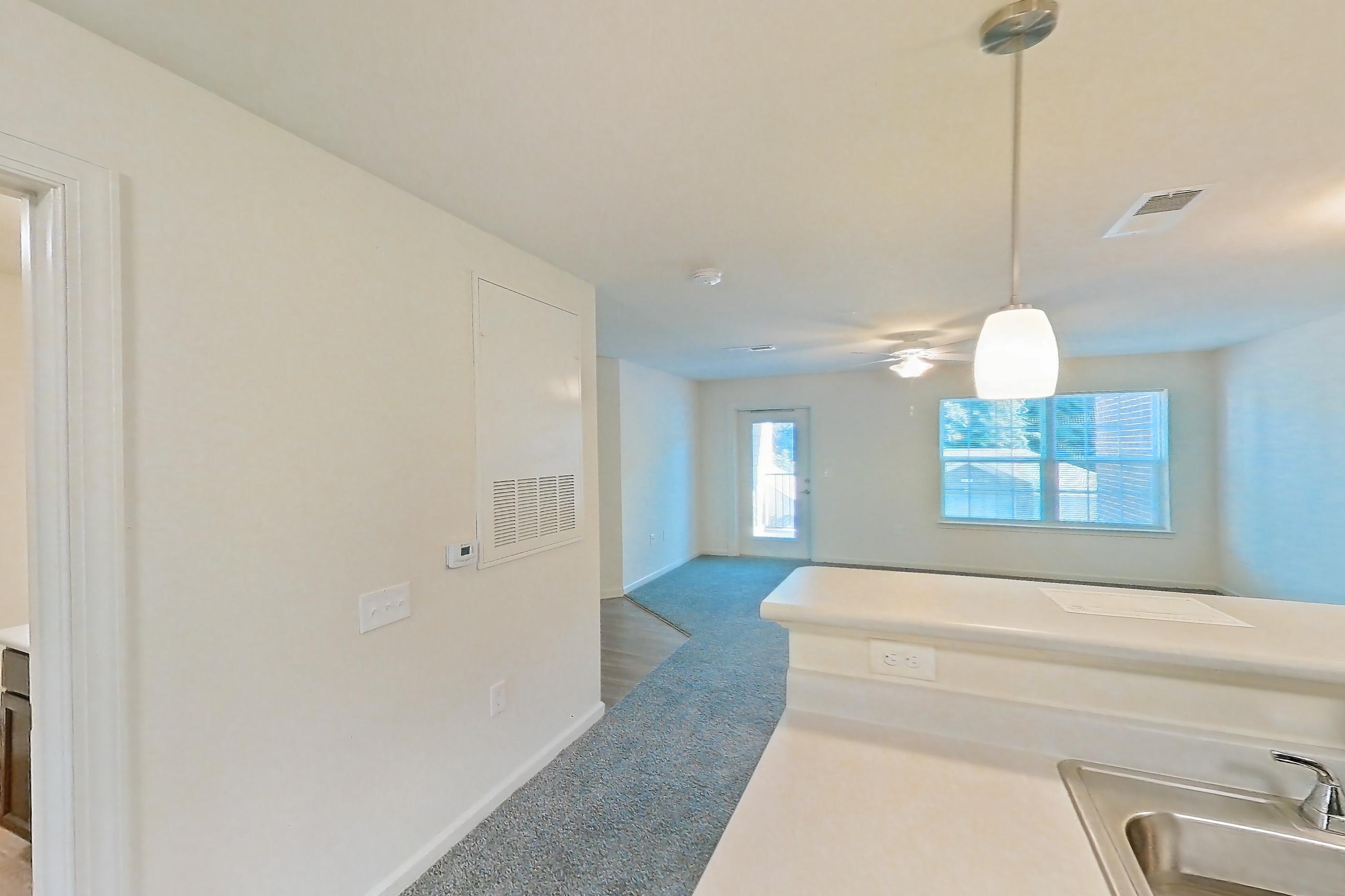 Kitchen with black appliances, electric range, light carpet, light countertops, light wood-finish flooring, oven/range, and refrigerator, Apartment 10O at Springbrook