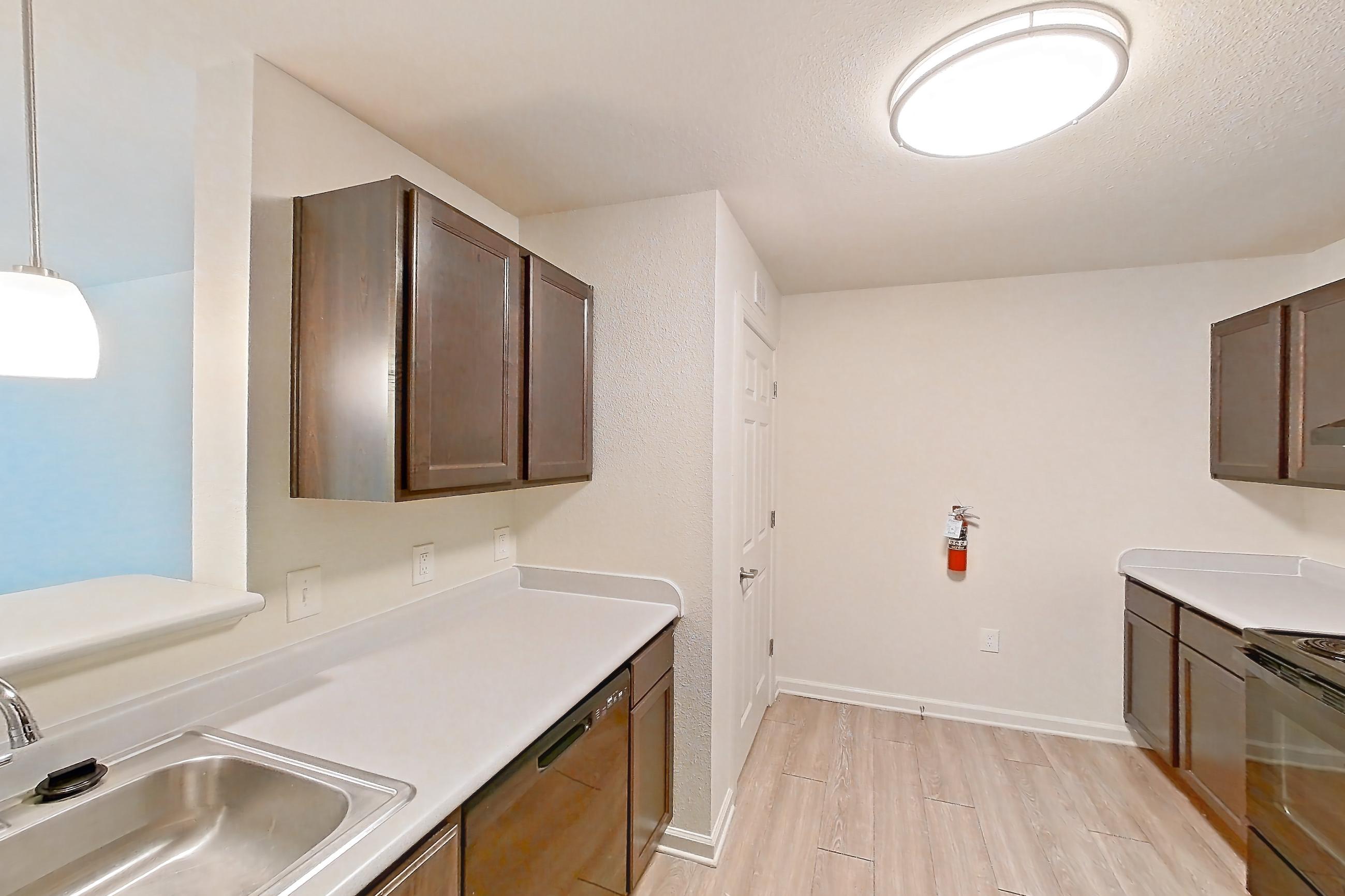 Kitchen with black appliances, dishwasher, electric range, light countertops, light wood-finish flooring, oven/range, and refrigerator, Apartment 4L at Springbrook