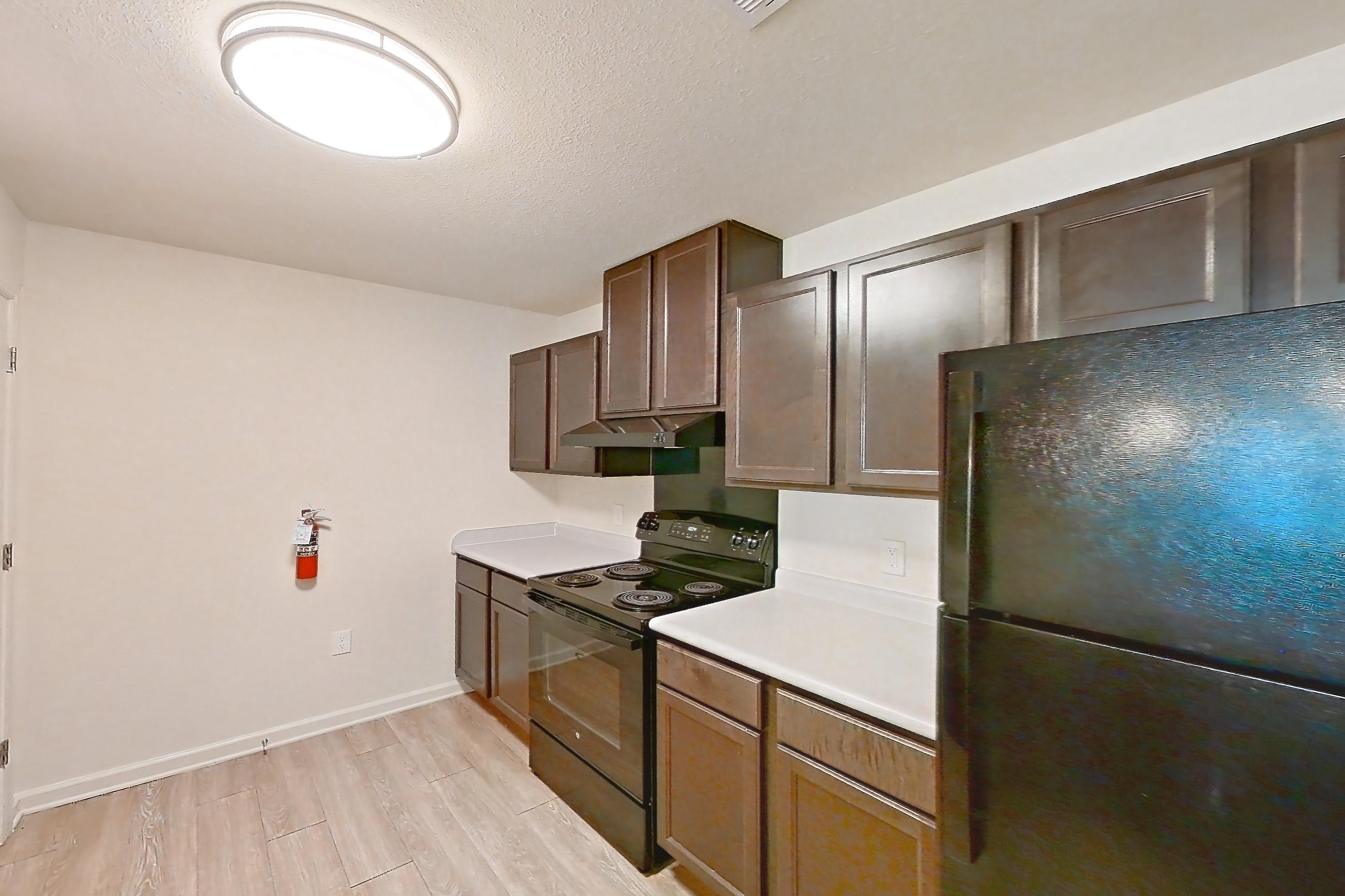 Kitchen with black appliances, dishwasher, electric range, light countertops, light wood-finish flooring, oven/range, and refrigerator, Apartment 4L at Springbrook