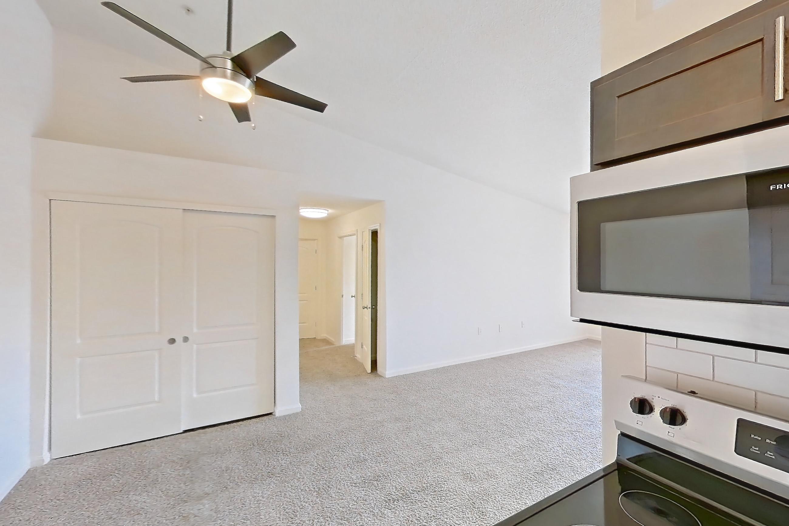Kitchen with electric range, light countertops, light stone countertops, light wood-finish flooring, microwave, oven/range, refrigerator, and stainless steel appliances, Apartment 2209-L at The Landings