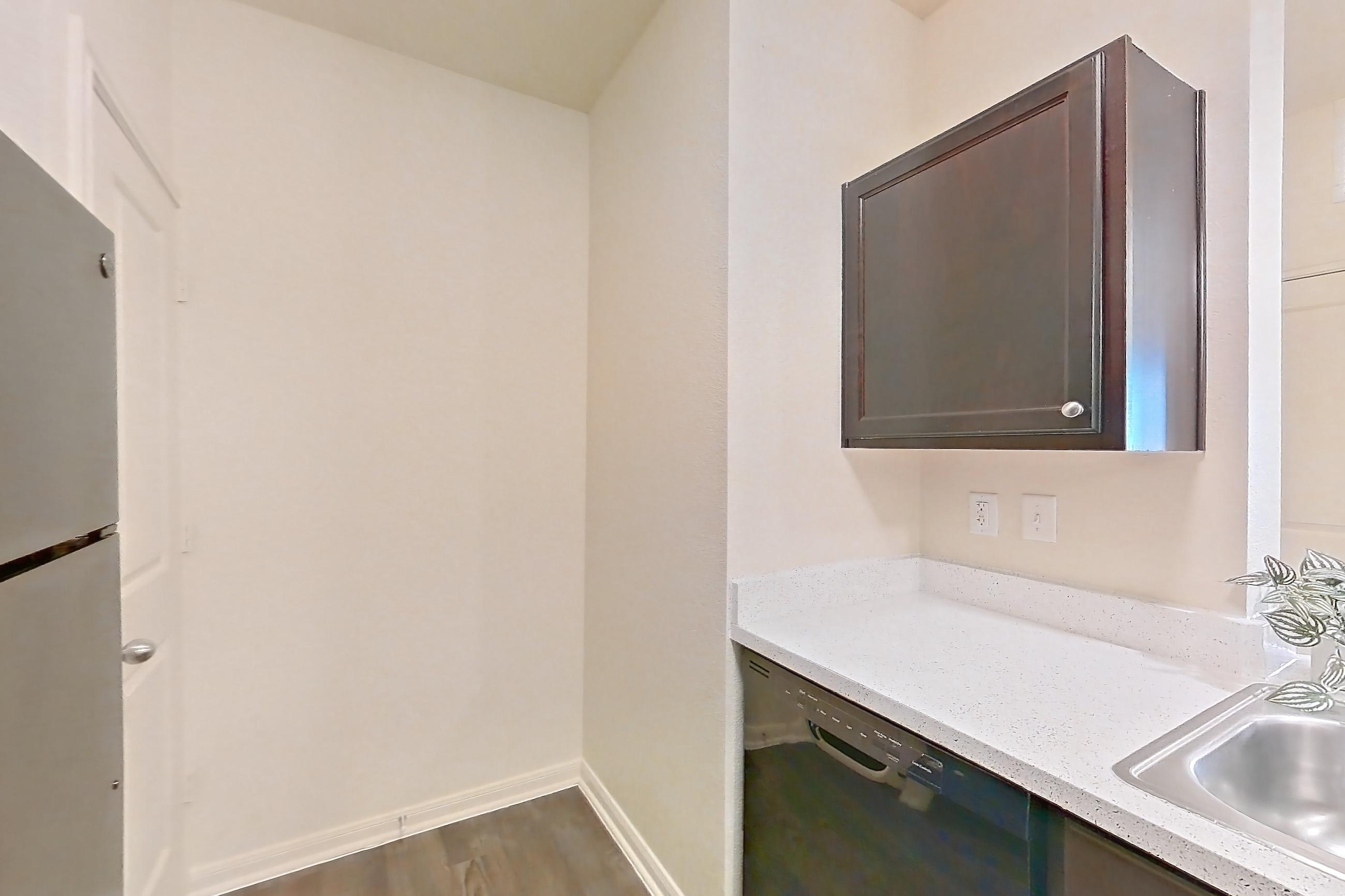 Kitchen with black appliances, dark carpet, dark wood-finish flooring, dishwasher, electric range, light countertops, light stone countertops, microwave, oven/range, and refrigerator, Apartment 1232 at William Cannon