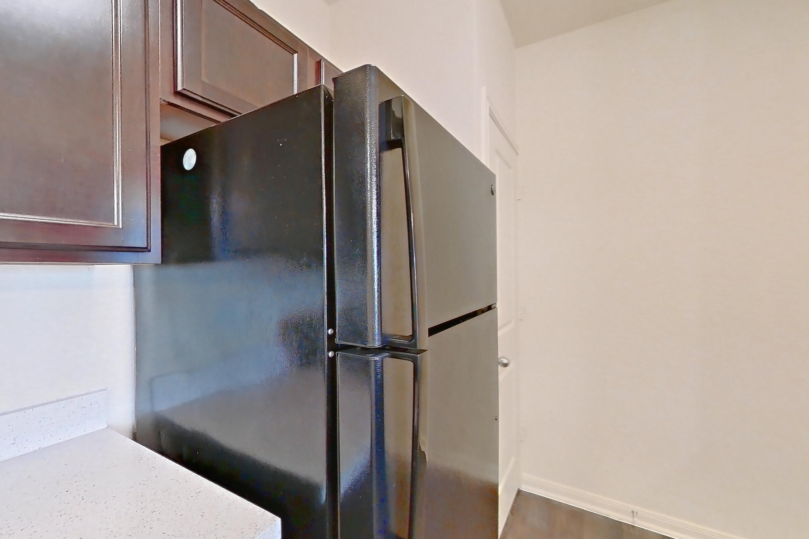 Kitchen with black appliances, dark carpet, dark wood-finish flooring, dishwasher, electric range, light countertops, light stone countertops, microwave, oven/range, and refrigerator, Apartment 1232 at William Cannon