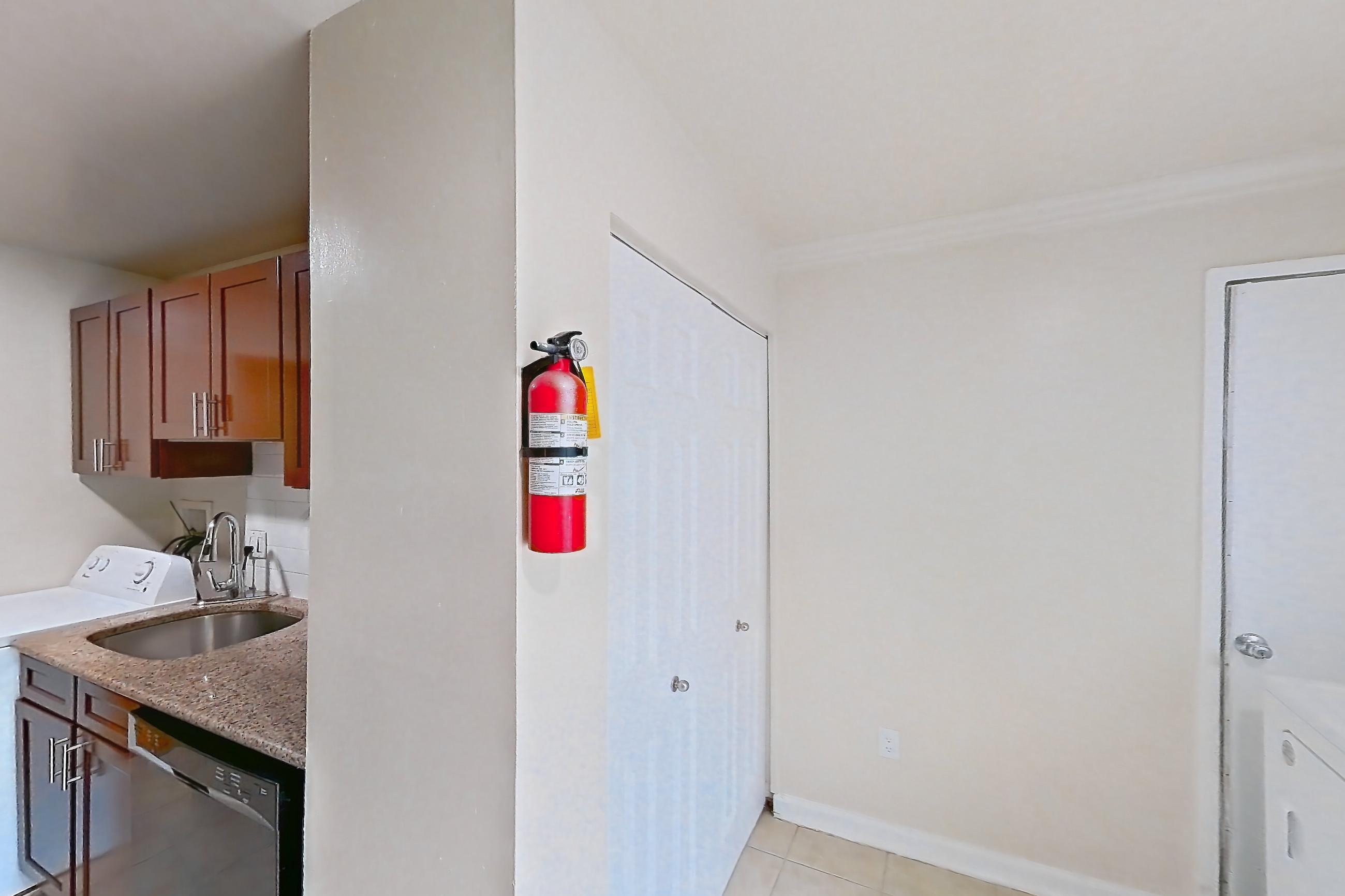 Kitchen with black appliances, dishwasher, gas range, in-unit laundry, light countertops, light stone countertops, light tile flooring, oven/range, refrigerator, and stainless steel appliances, Apartment 9320ER24 at Franklin Park at Greenbelt Station