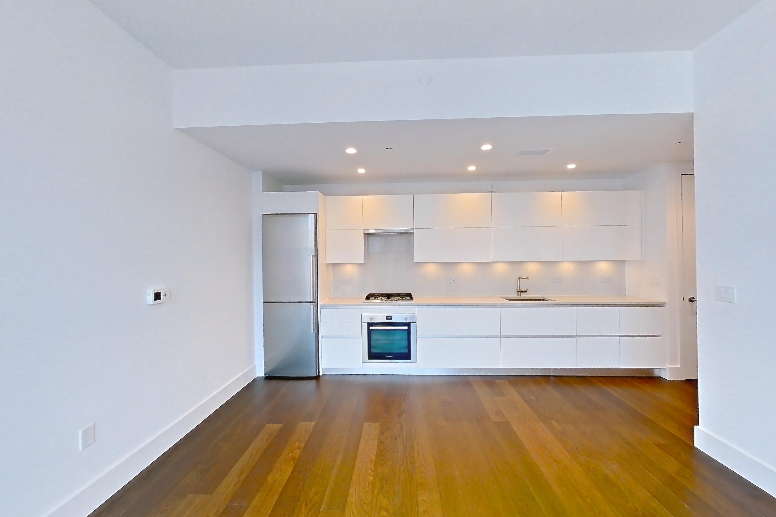 Living room with cooktop, dark wood-finish flooring, gas cooktop, oven/range, refrigerator, stainless steel appliances, and wood-finish flooring, Apartment 38A at Summit NYC