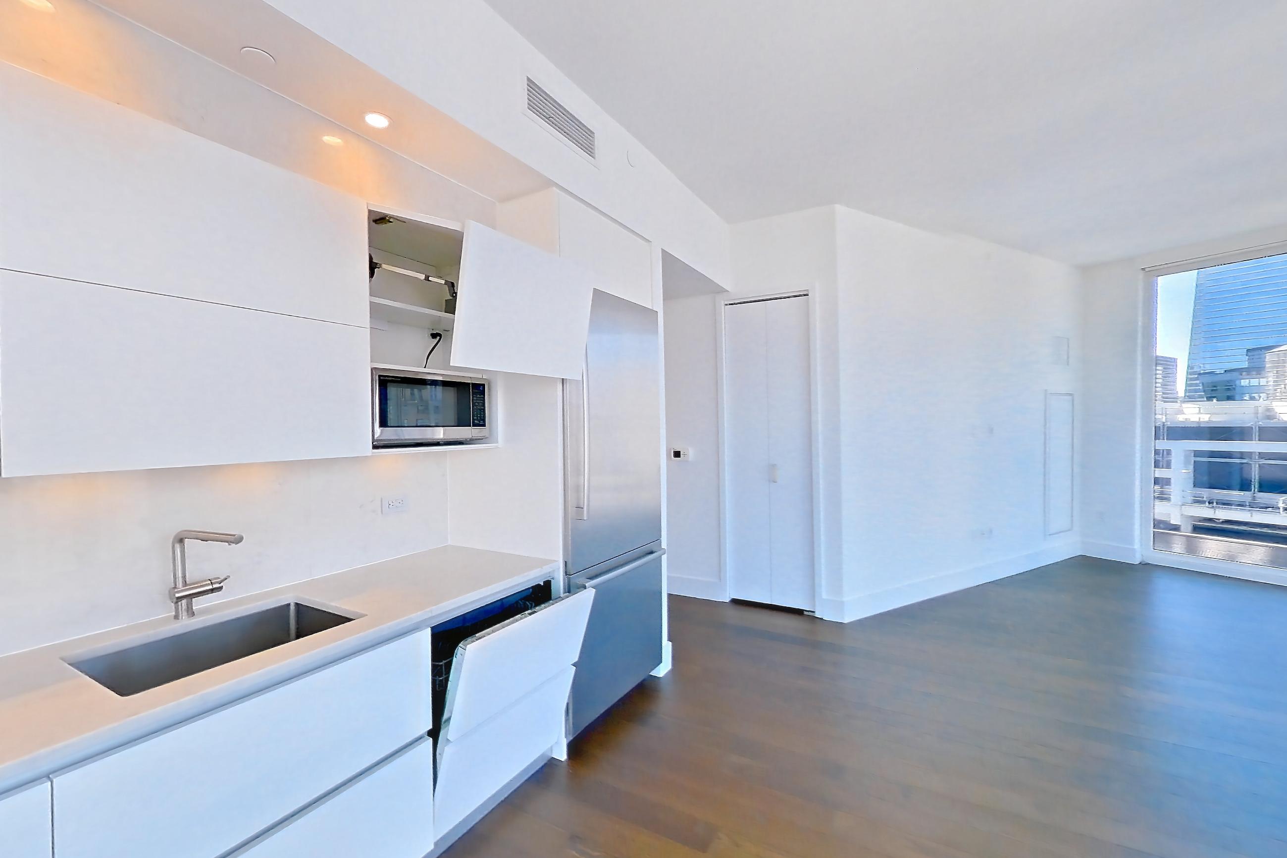 Kitchen with cooktop, dark wood-finish flooring, gas cooktop, light stone countertops, oven/range, refrigerator, stainless steel appliances, white appliances, and wood-finish flooring, Apartment 35L at Summit NYC