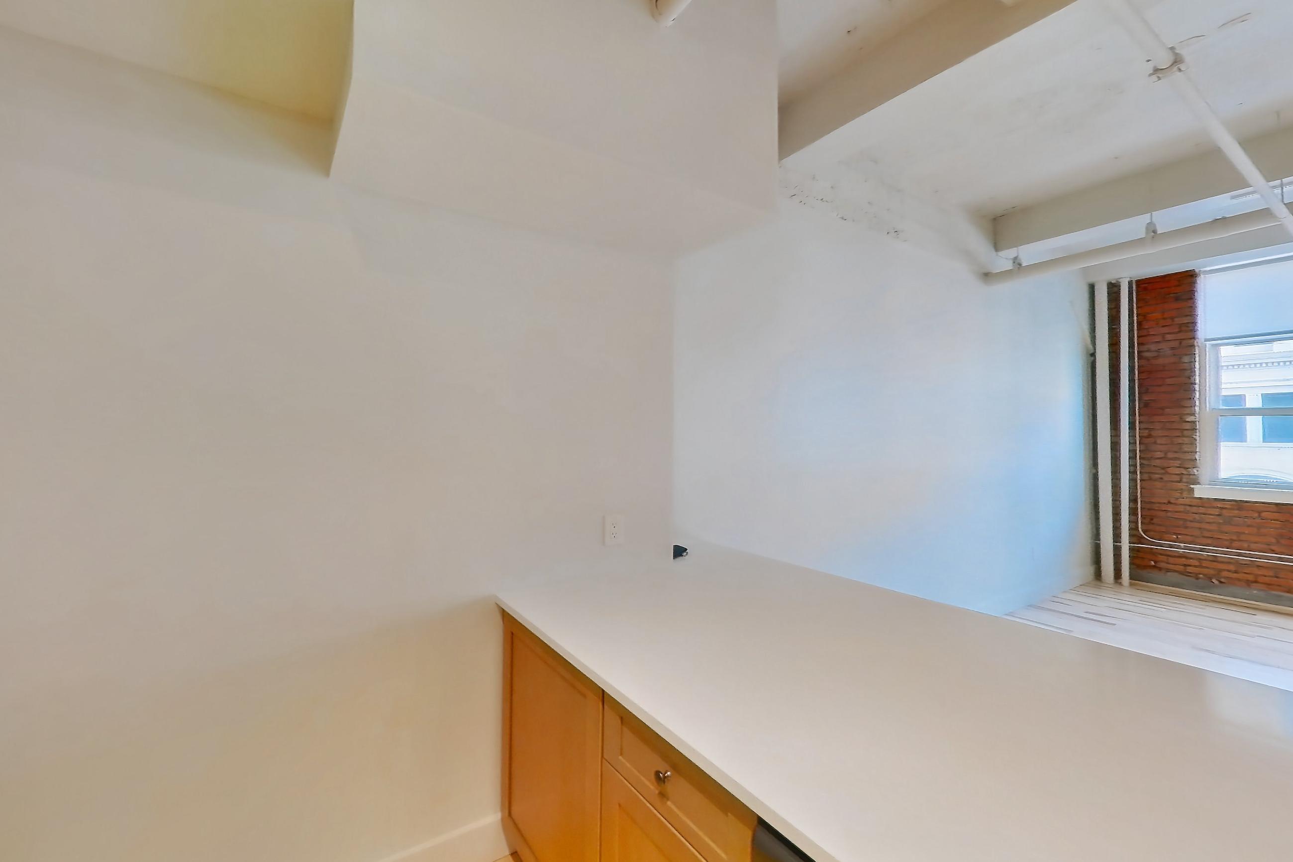 Kitchen with dishwasher, light countertops, light wood-finish flooring, oven/range, refrigerator, stainless steel appliances, and water & ice dispenser, Apartment 309 at Temple Building