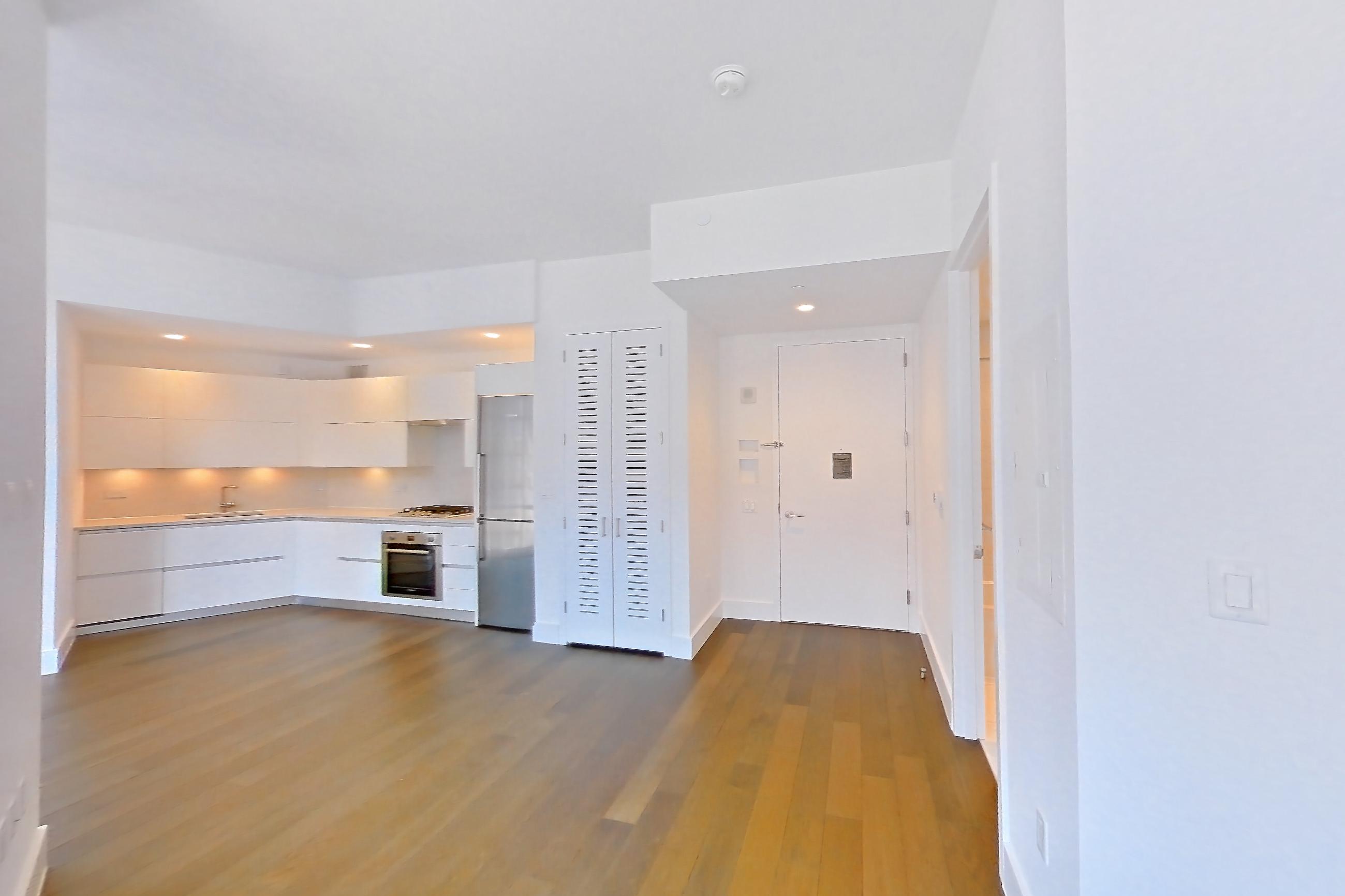 Living space with cooktop, dark wood-finish flooring, gas cooktop, light countertops, oven/range, refrigerator, stainless steel appliances, white appliances, and wood-finish flooring, Apartment 28M at Summit NYC