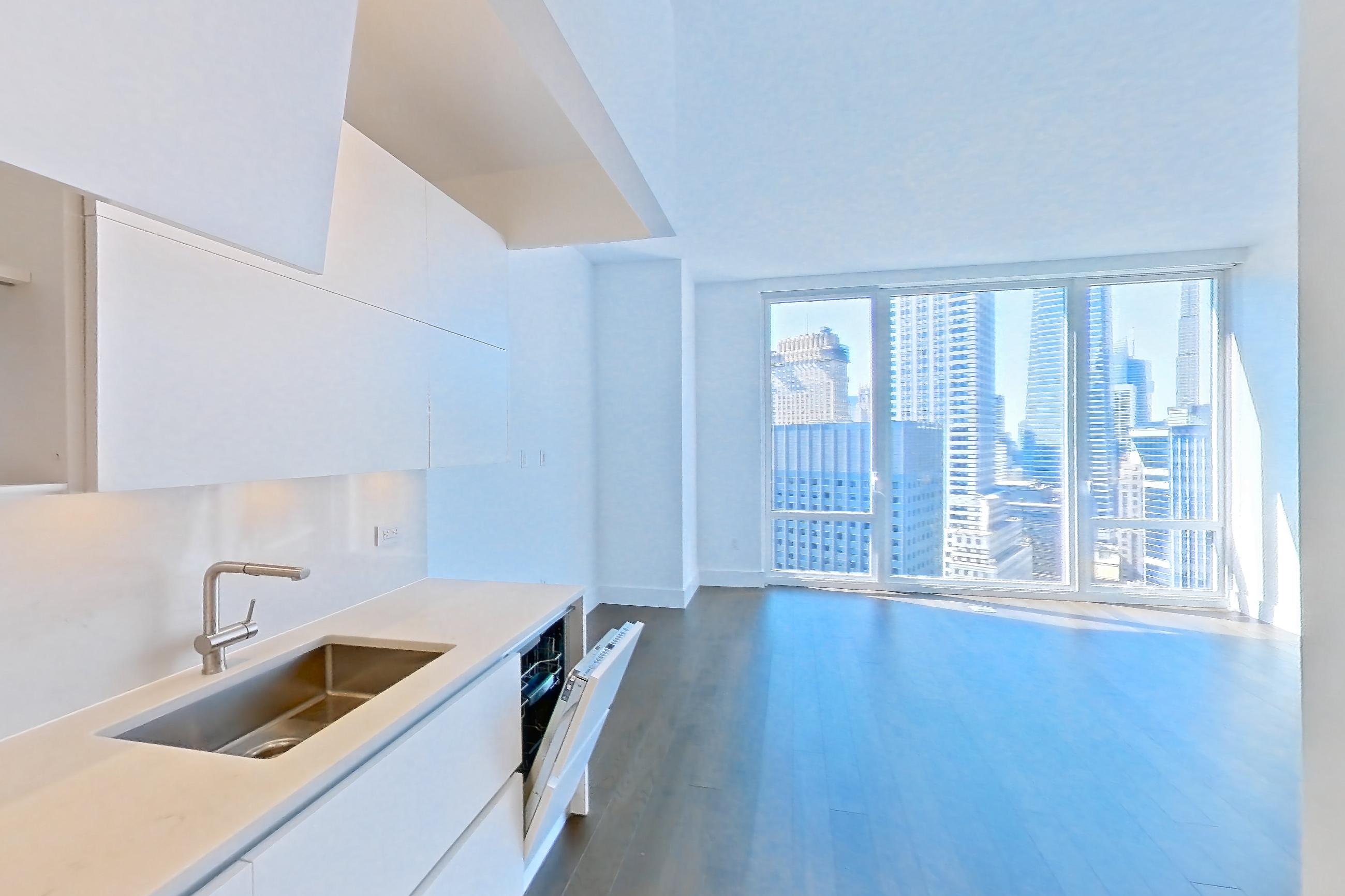 Kitchen with cooktop, dark wood-finish flooring, dishwasher, gas cooktop, light countertops, light stone countertops, microwave, oven/range, refrigerator, skyline view, stainless steel appliances, and wood-finish flooring, Apartment 38C at Summit NYC