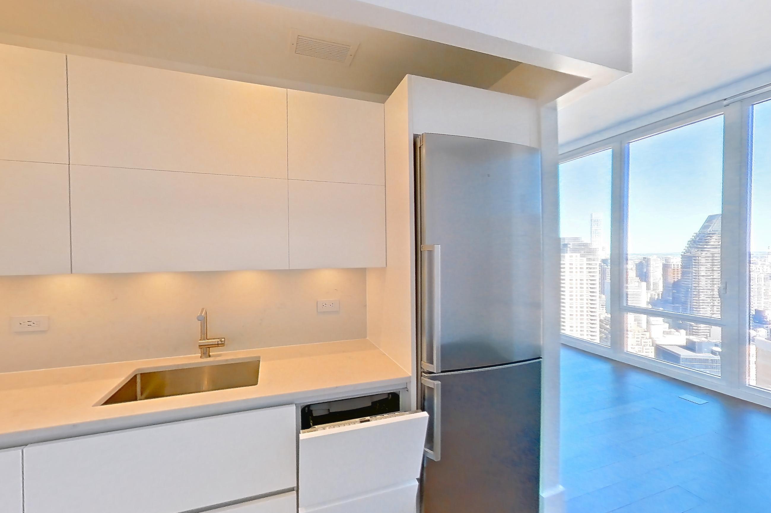 Kitchen with cooktop, dark wood-finish flooring, gas cooktop, light countertops, microwave, oven/range, refrigerator, stainless steel appliances, and wood-finish flooring, Apartment 38J at Summit NYC
