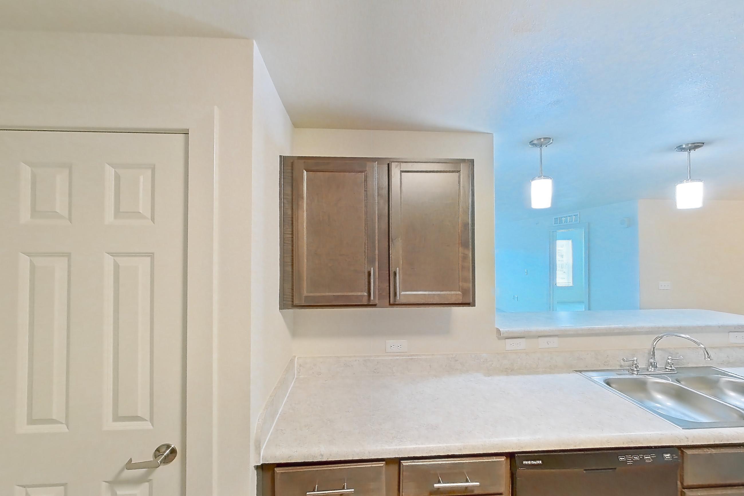 Kitchen with black appliances, dishwasher, electric range, light countertops, light wood-finish flooring, oven/range, range hood, refrigerator, and stainless steel appliances, Apartment 8O at The Creek at Cottonwood