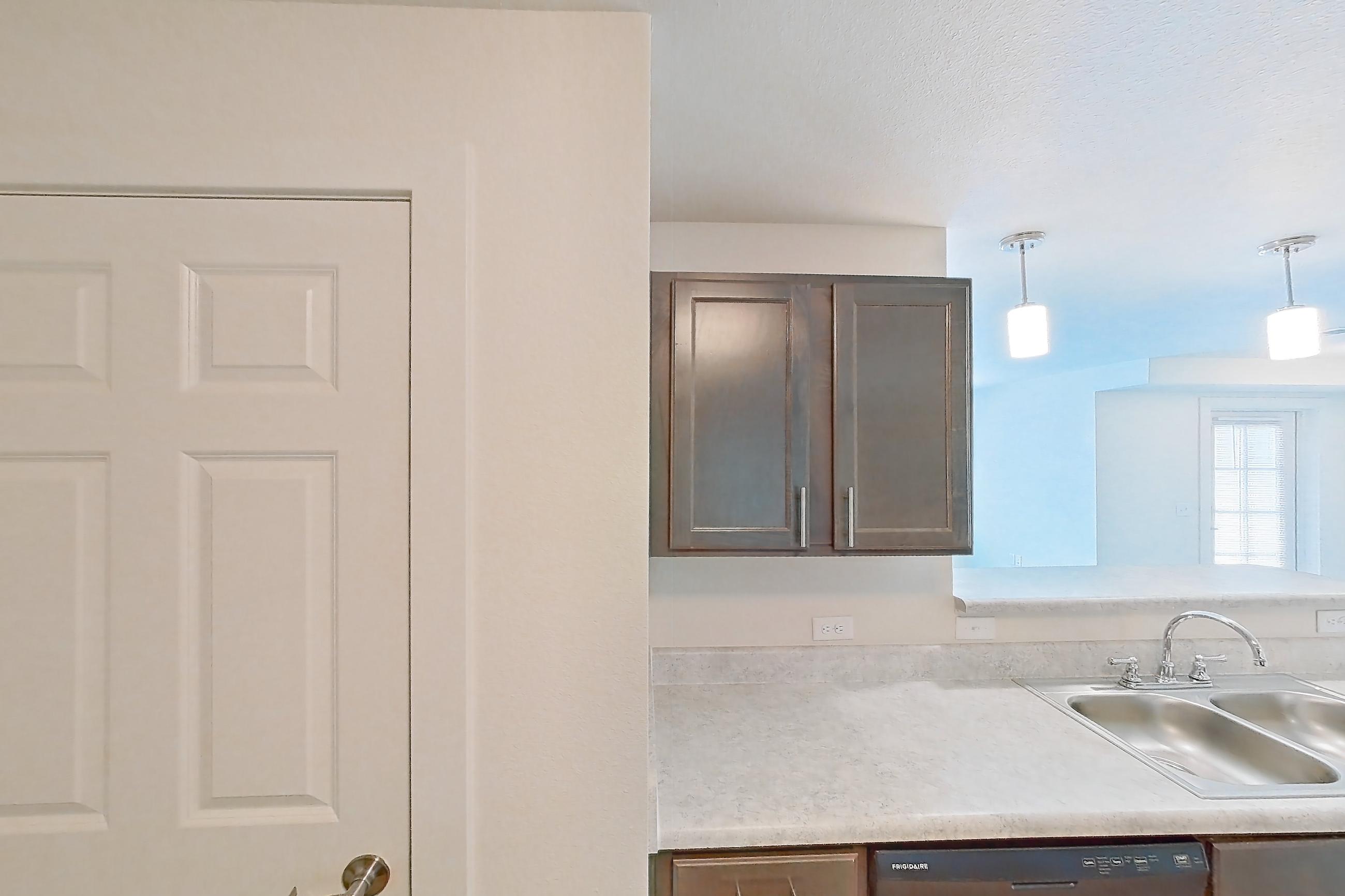 Kitchen with black appliances, dishwasher, electric range, light countertops, light wood-finish flooring, oven/range, range hood, refrigerator, and stainless steel appliances, Apartment 4Q at The Creek at Cottonwood