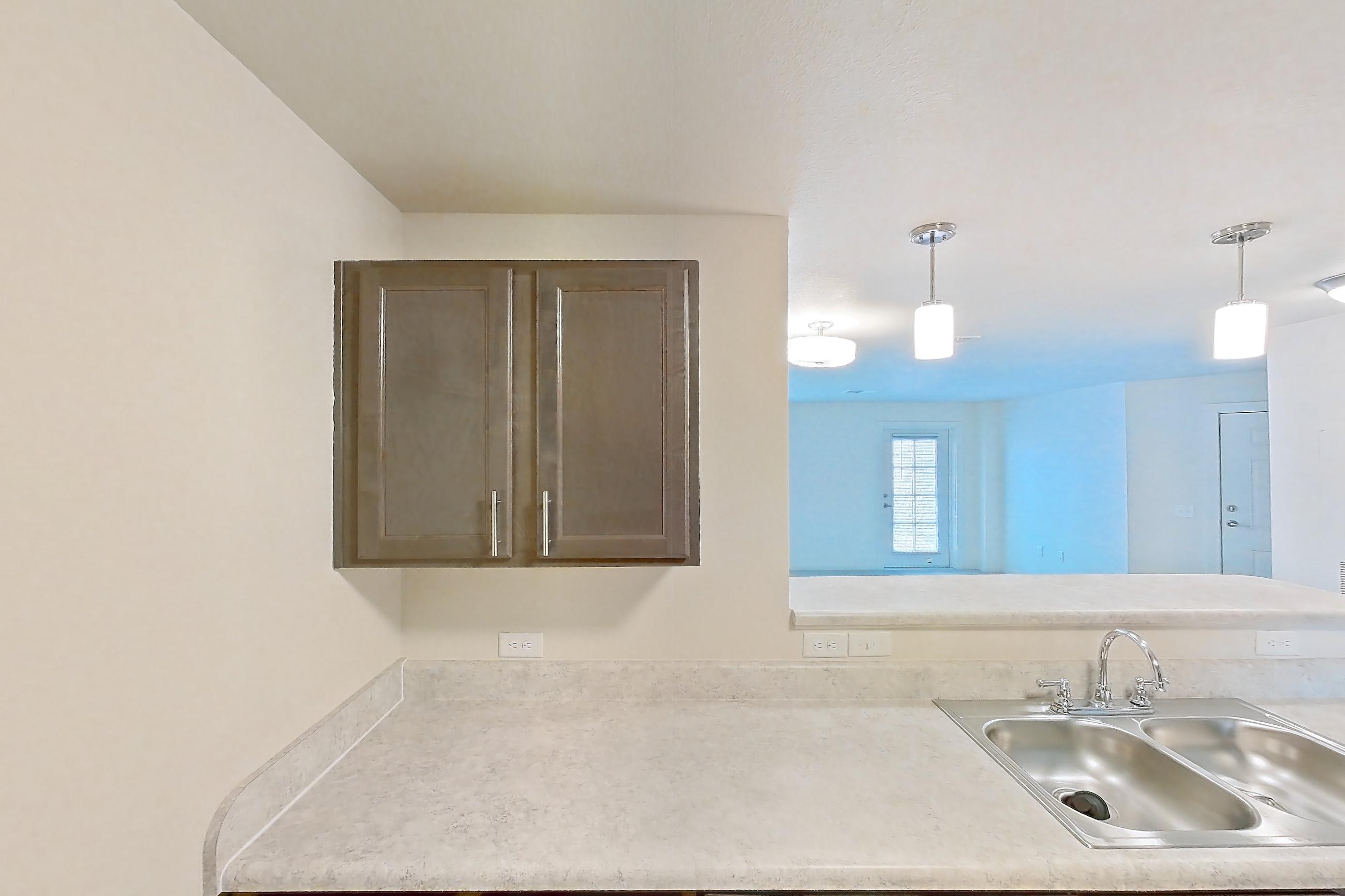 Kitchen with black appliances, dishwasher, electric range, light countertops, light wood-finish flooring, oven/range, range hood, refrigerator, and stainless steel appliances, Apartment 2D at The Creek at Cottonwood