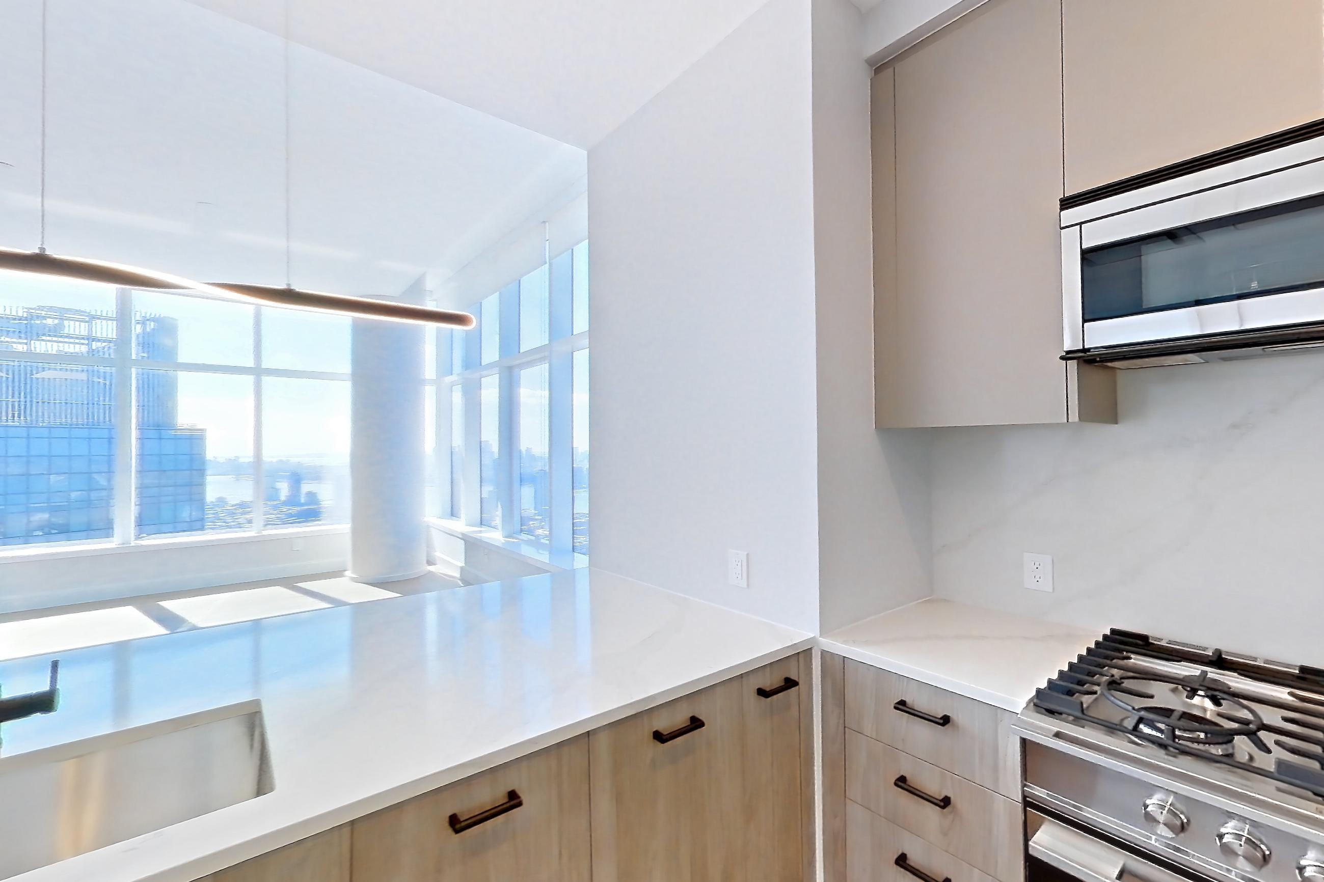 Kitchen with gas range, light countertops, light stone countertops, light wood-finish flooring, microwave, oven/range, and stainless steel appliances, Apartment PH3C at Lumen