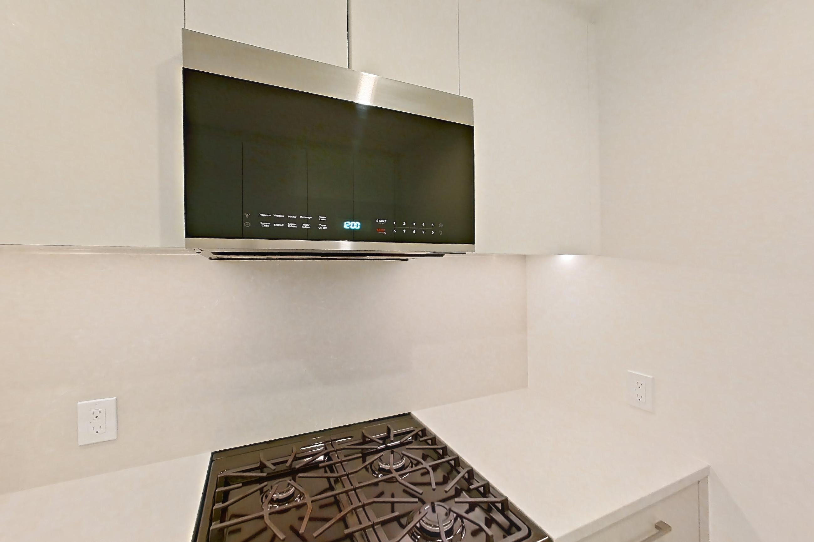 Kitchen with dishwasher, gas range, light countertops, light stone countertops, light wood-finish flooring, oven/range, refrigerator, and stainless steel appliances, Apartment 37L at Lumen
