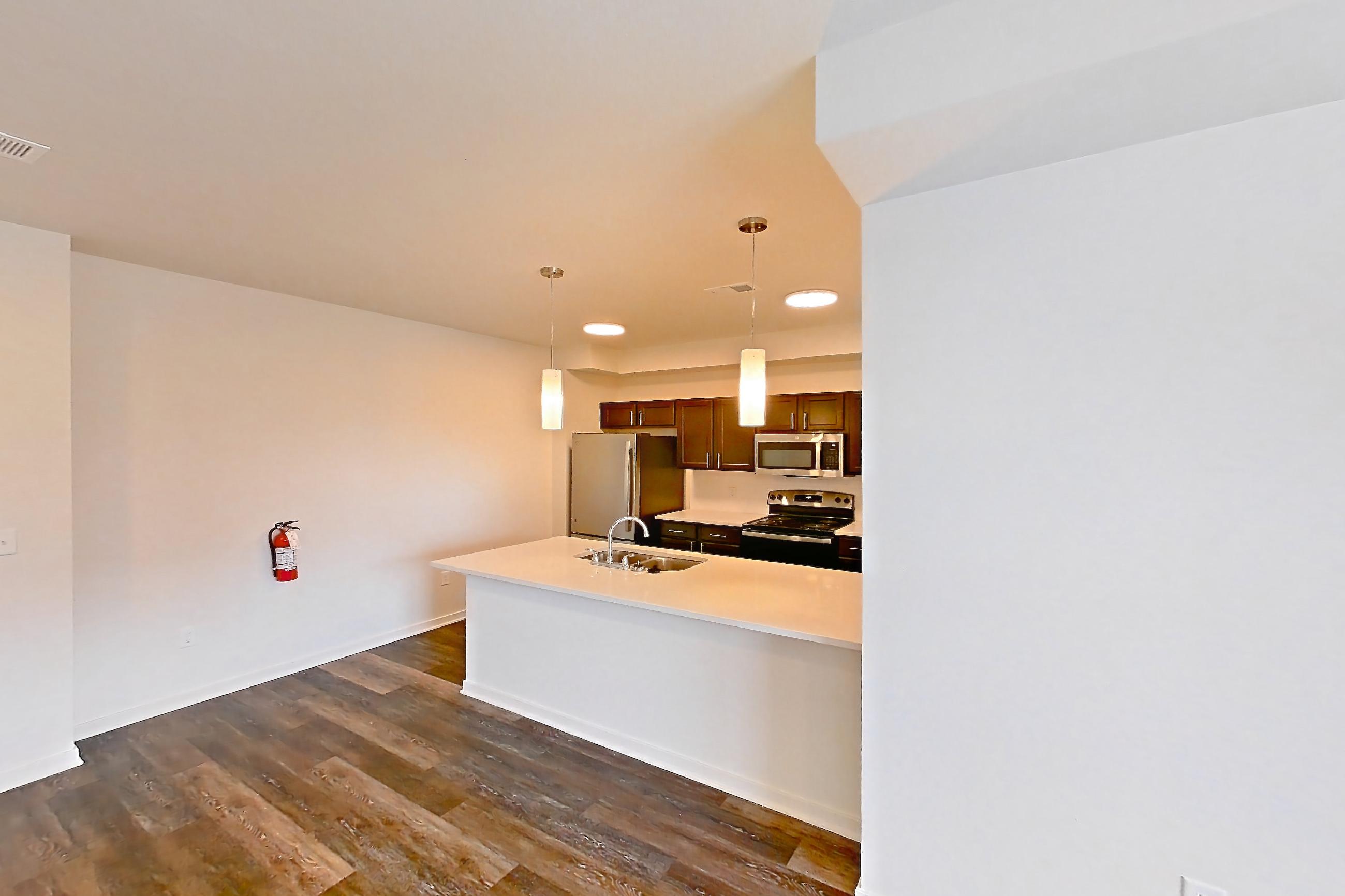 Living space with dark wood-finish flooring, electric range, light countertops, oven/range, refrigerator, stainless steel appliances, and white appliances, Apartment 3204 at Village at Thorncreek