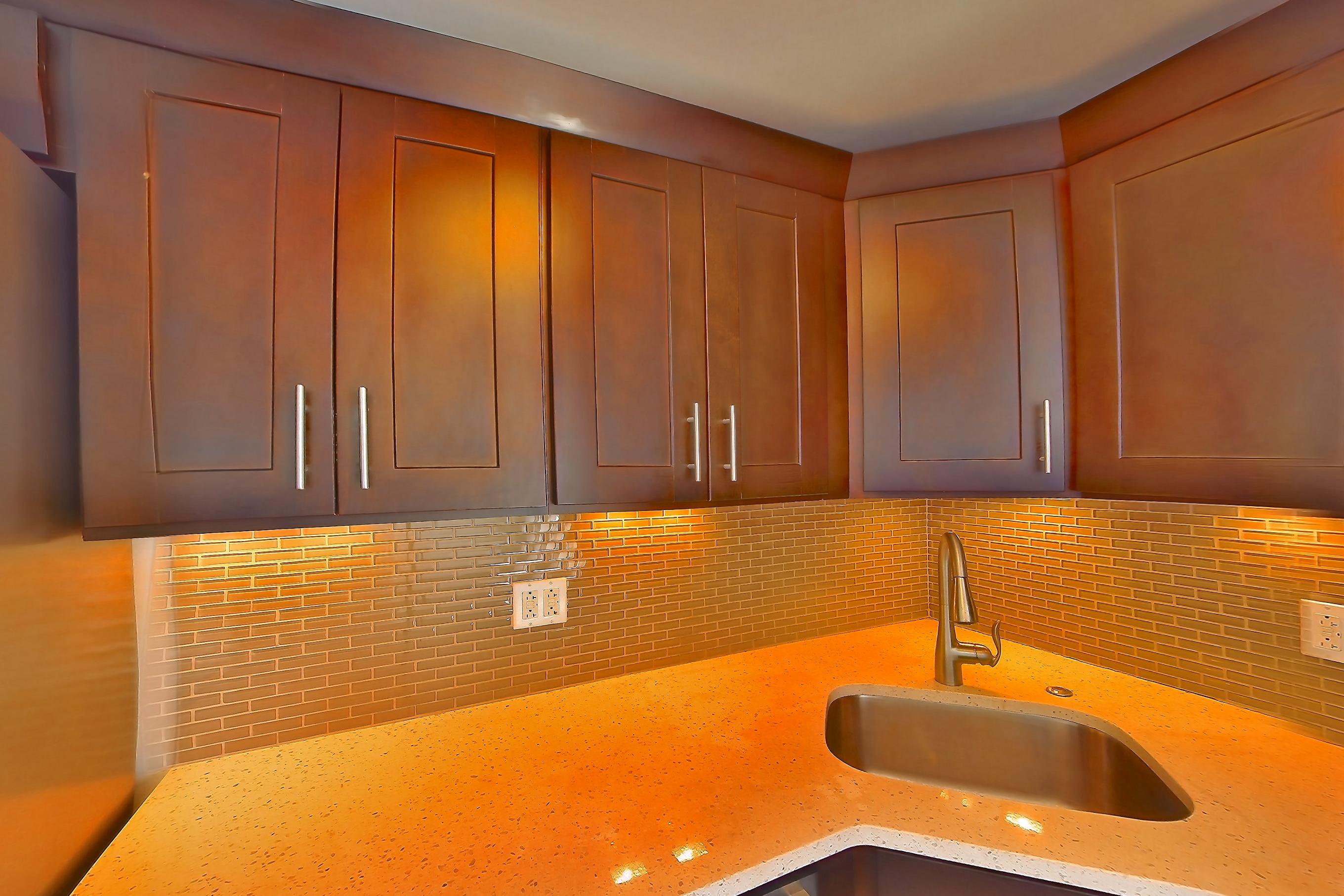 Kitchen with dark wood-finish flooring, dishwasher, gas range, light countertops, light stone countertops, microwave, oven/range, refrigerator, stainless steel appliances, and white appliances, Apartment 1401 at Stonehenge Leasing