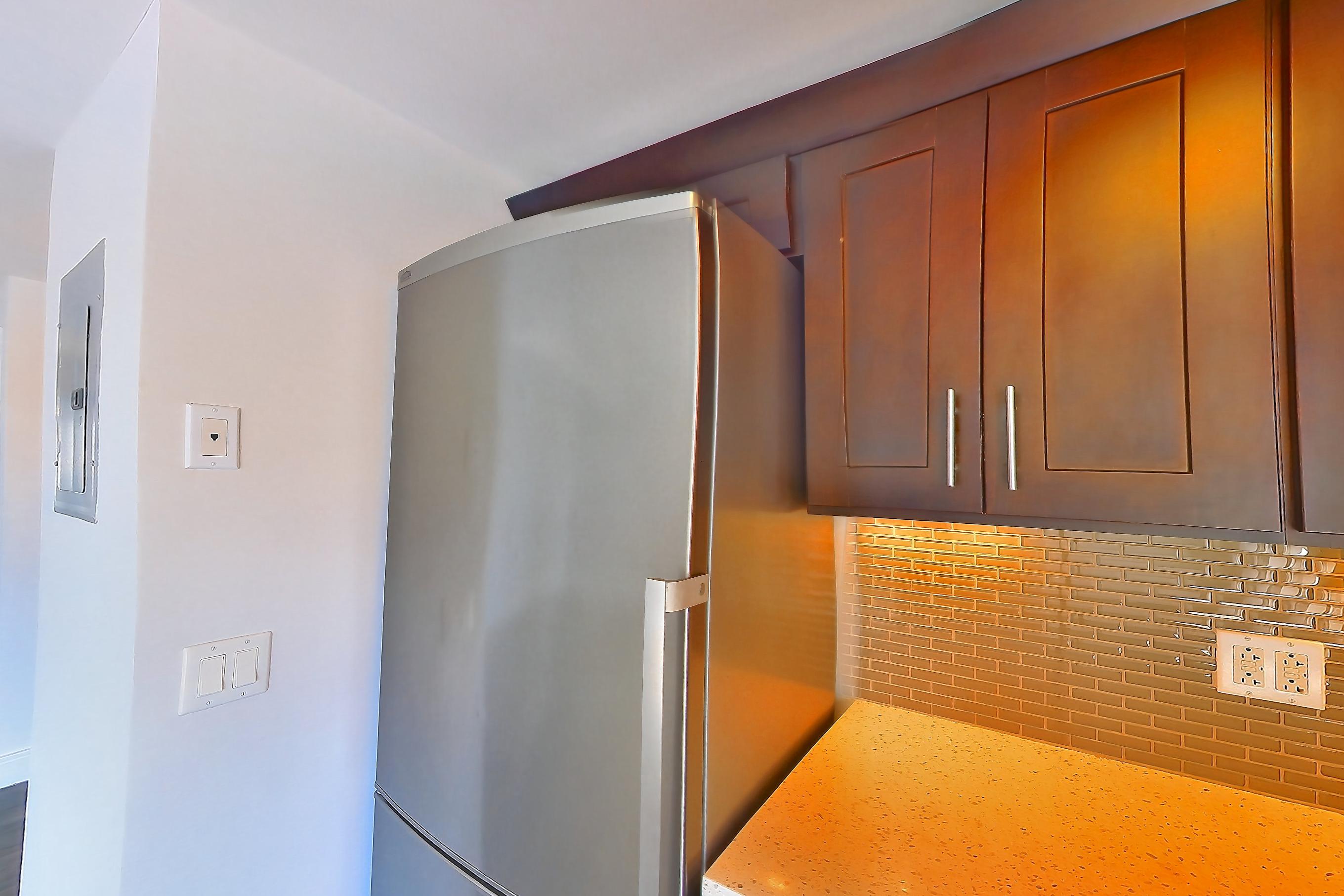 Kitchen with dark wood-finish flooring, dishwasher, gas range, light countertops, light stone countertops, microwave, oven/range, refrigerator, stainless steel appliances, and white appliances, Apartment 1401 at Stonehenge Leasing