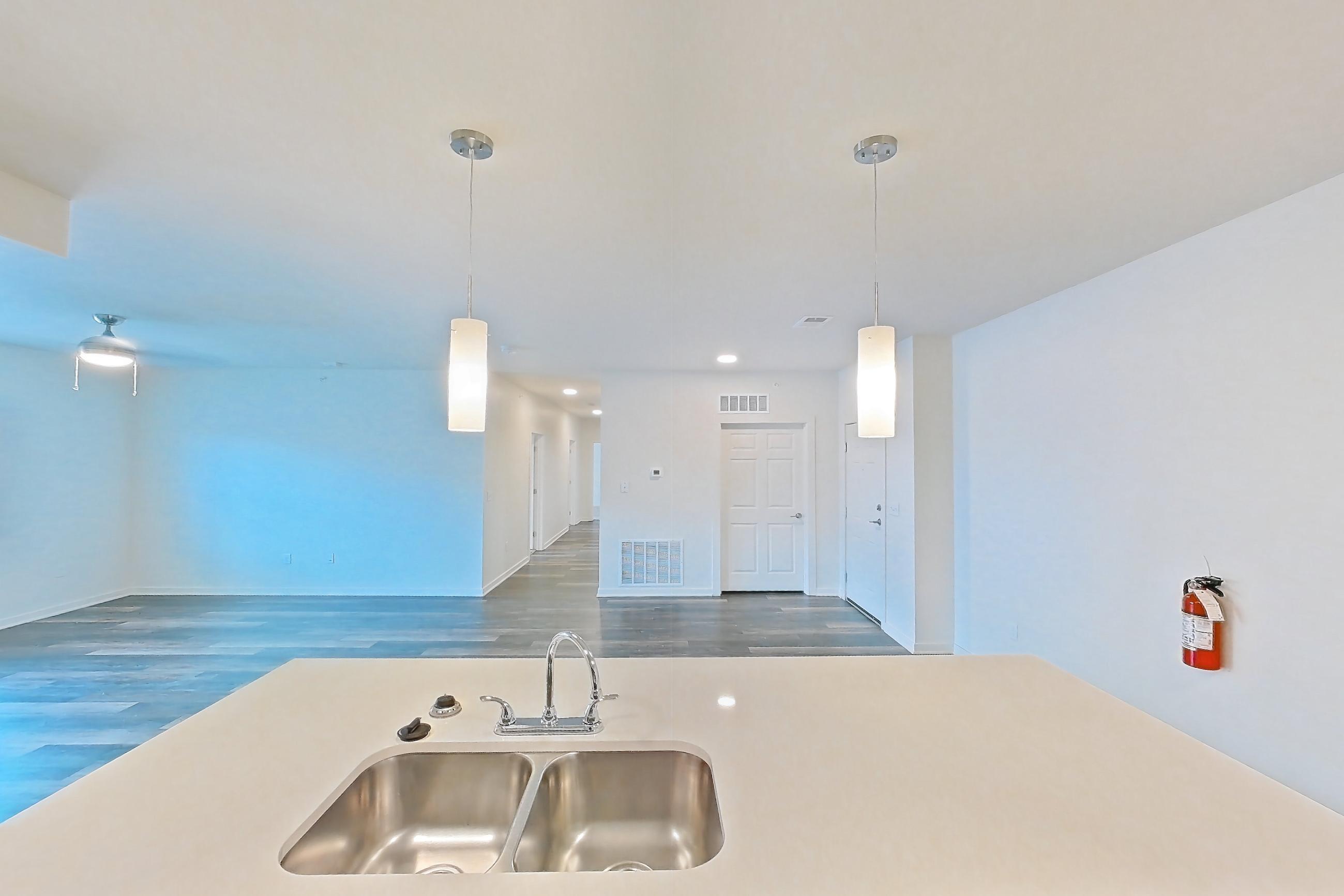 Kitchen with black appliances, dark wood-finish flooring, dishwasher, electric range, light countertops, microwave, oven/range, refrigerator, and stainless steel appliances, Apartment 3205 at Village at Thorncreek
