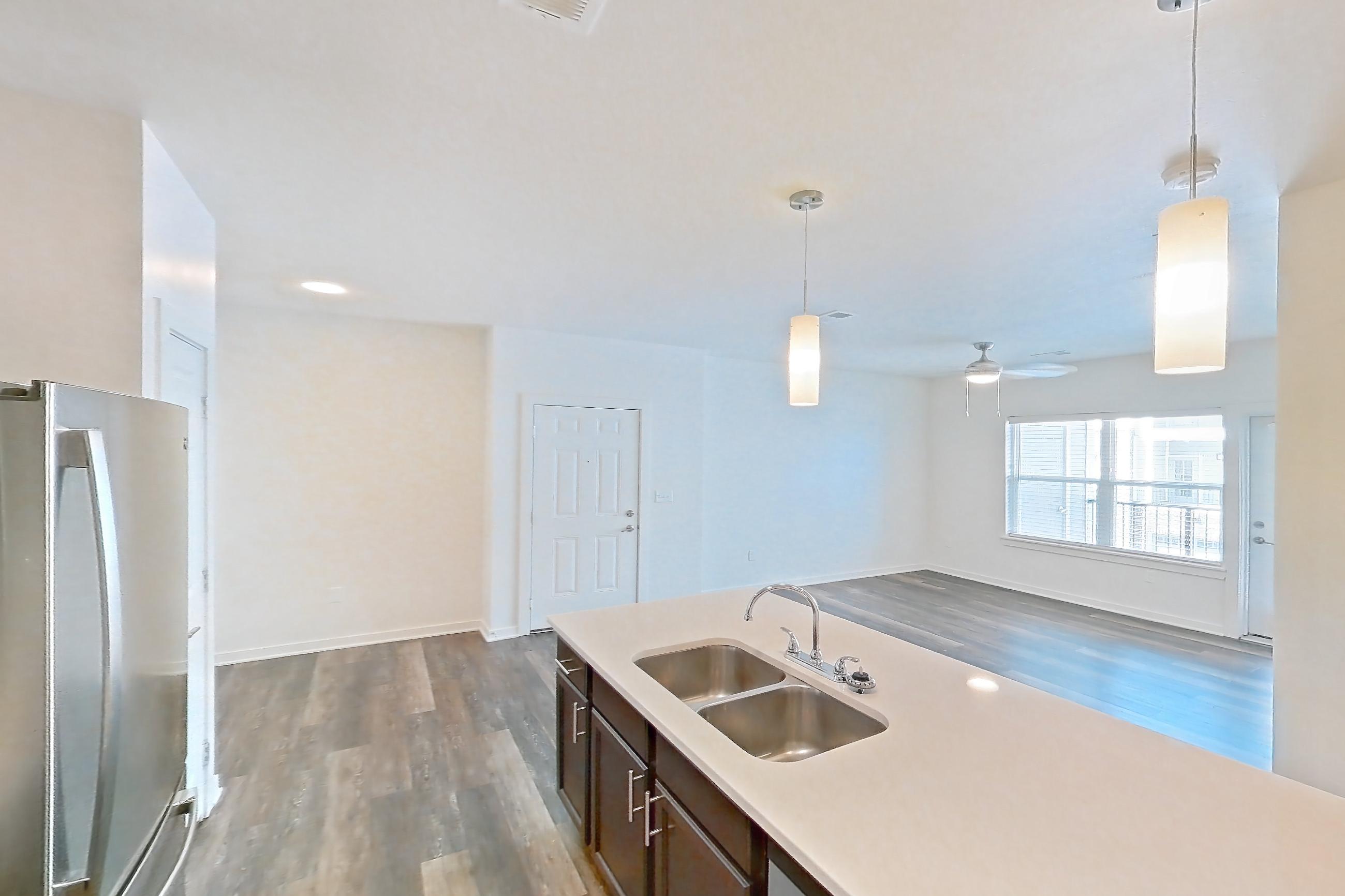 Kitchen with black appliances, dark wood-finish flooring, dishwasher, electric range, light countertops, microwave, oven/range, refrigerator, and stainless steel appliances, Apartment 11201 at Village at Thorncreek