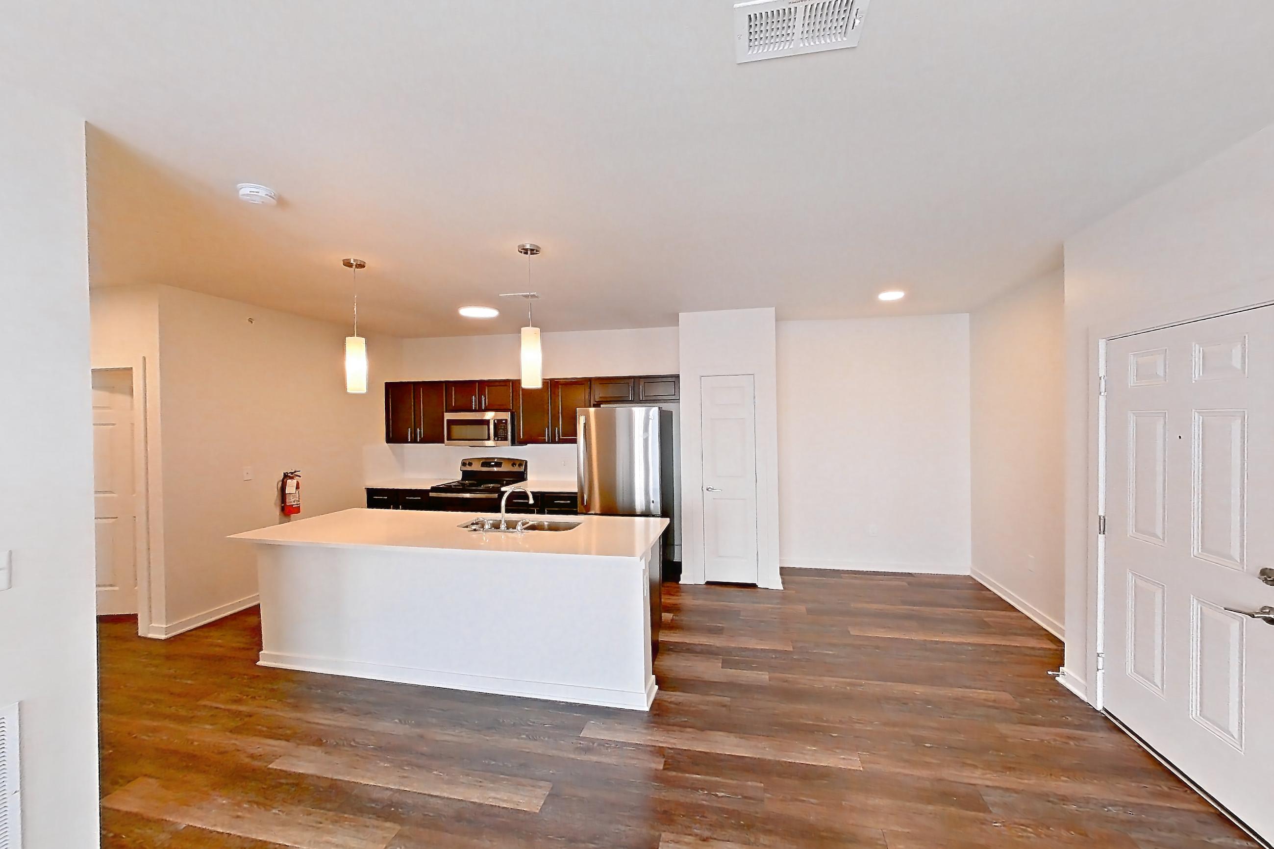 Living space with dark wood-finish flooring, oven/range, refrigerator, and stainless steel appliances, Apartment 11201 at Village at Thorncreek